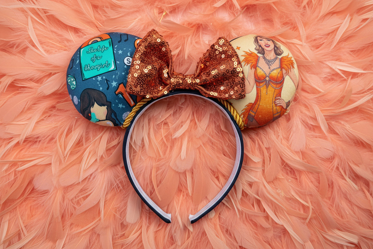 Decorative mouse ears inspired by TS12 on a black headband with a orange sequin bow and character designs. Shown on a pink feather background