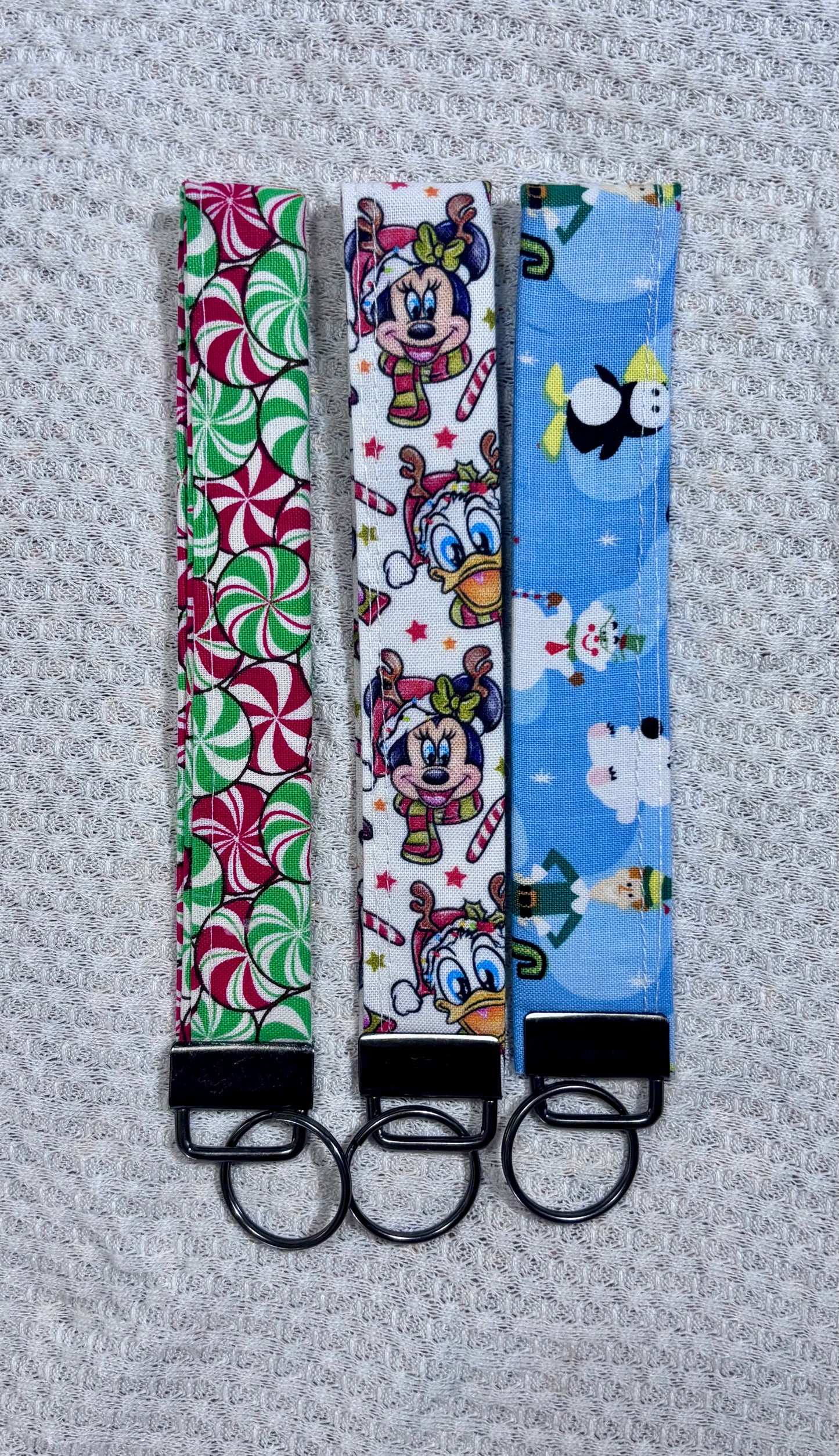 Three colorful keychains with different patterns on a textured gray background