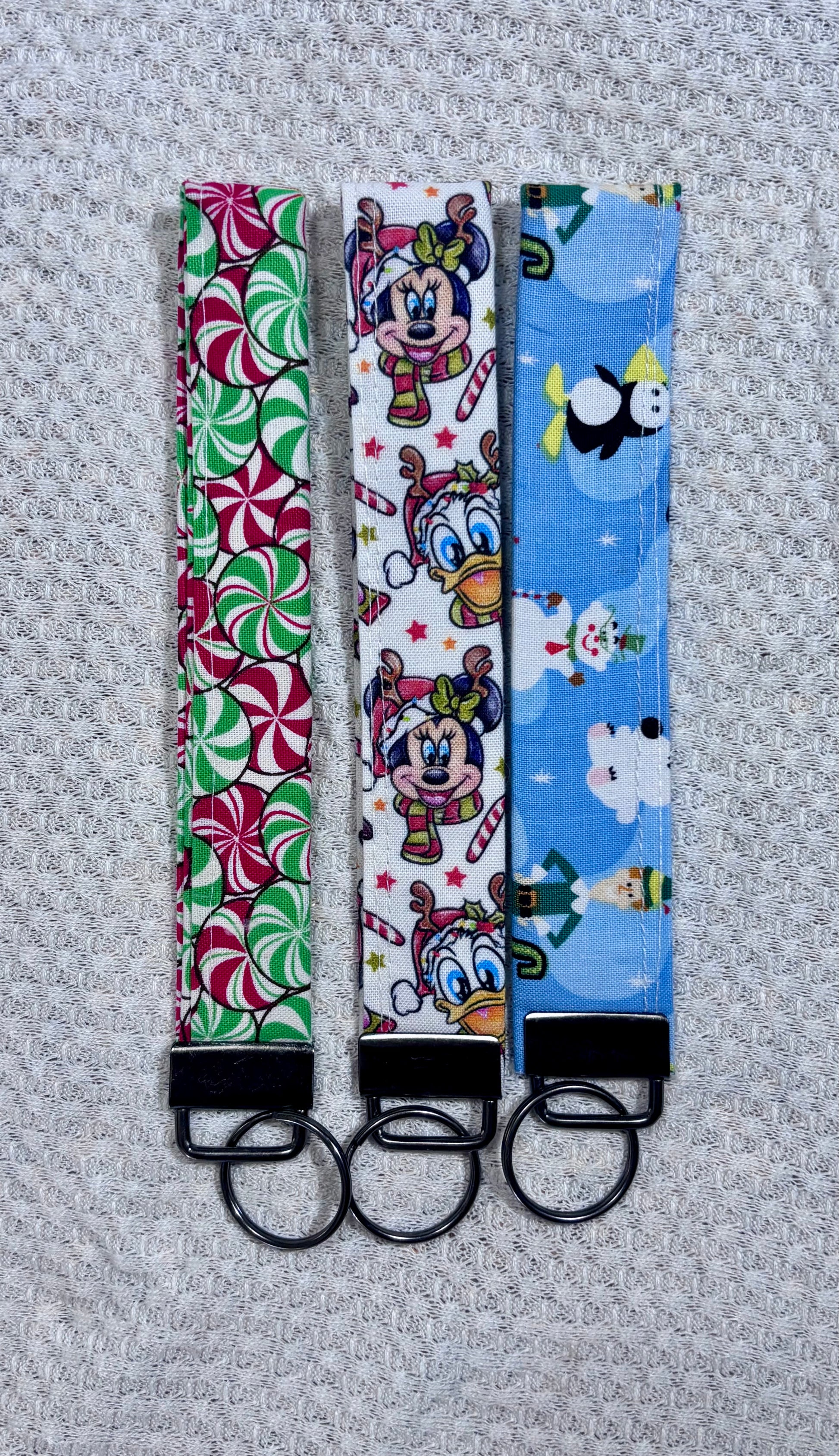 Three colorful keychains with different patterns on a textured gray background