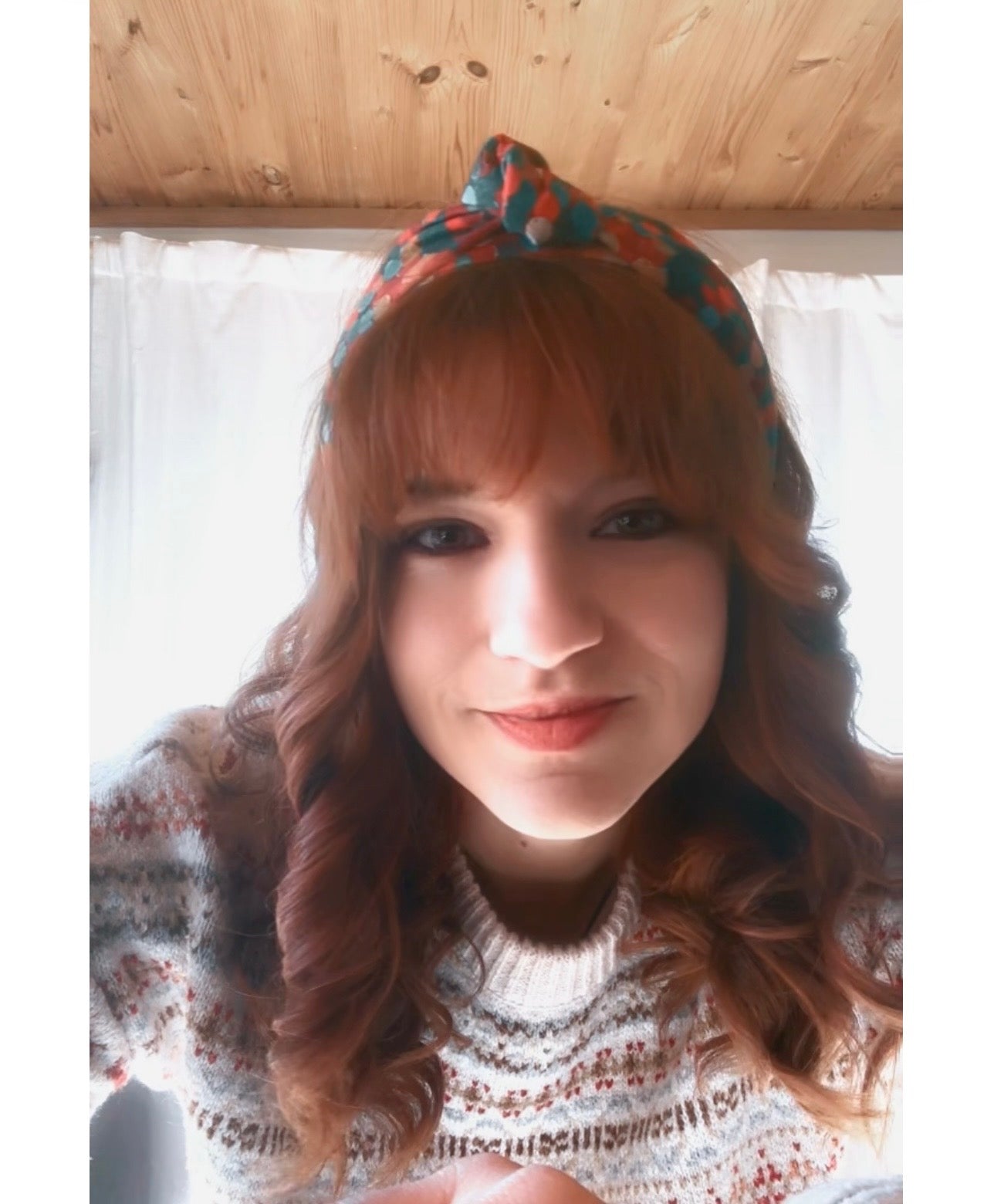 Woman wearing the Christmas Colors patterned headband and a sweater with a white background