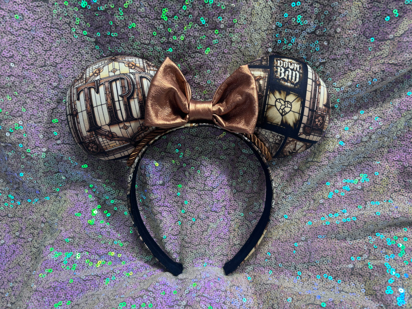 Mouse ears with a rose gold pleather bow and decorative elements on a textured purple background