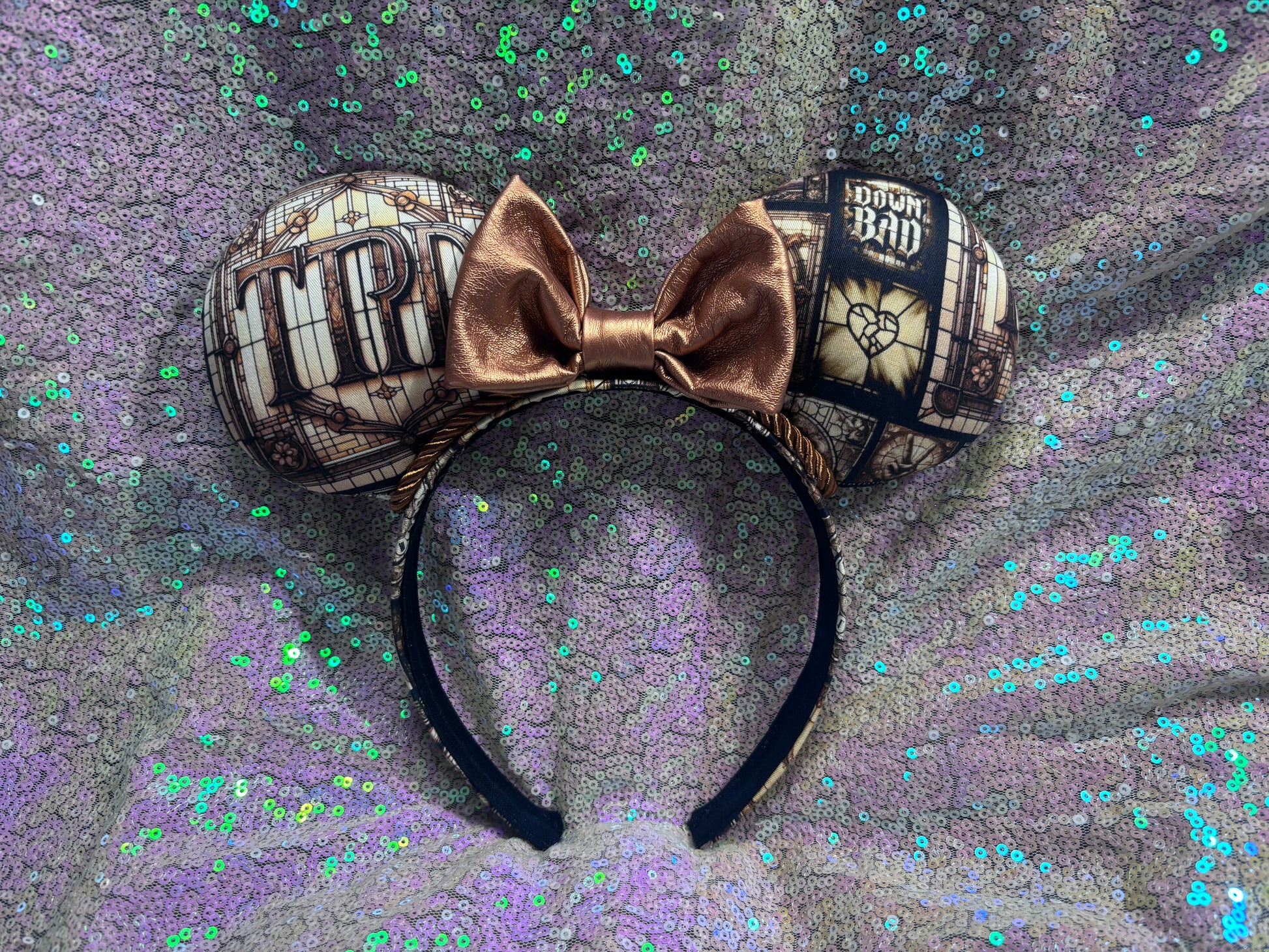 Mouse ears with a rose gold pleather bow and decorative elements on a textured purple background