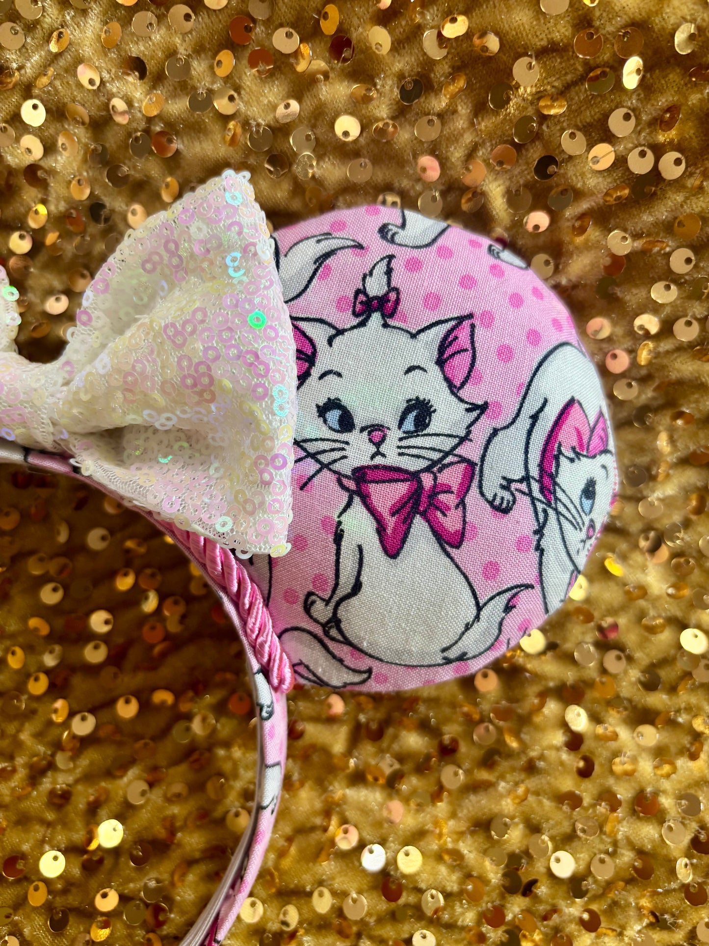 Pink mouse ear headband with white bow shown on a gold glitter background