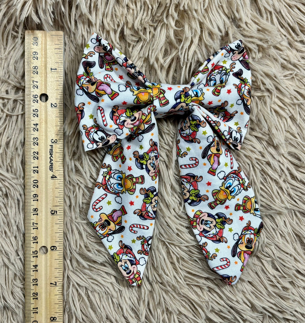 A fabric-covered headband with a colorful cartoon character print on a white background, displayed on a beige shag rug.