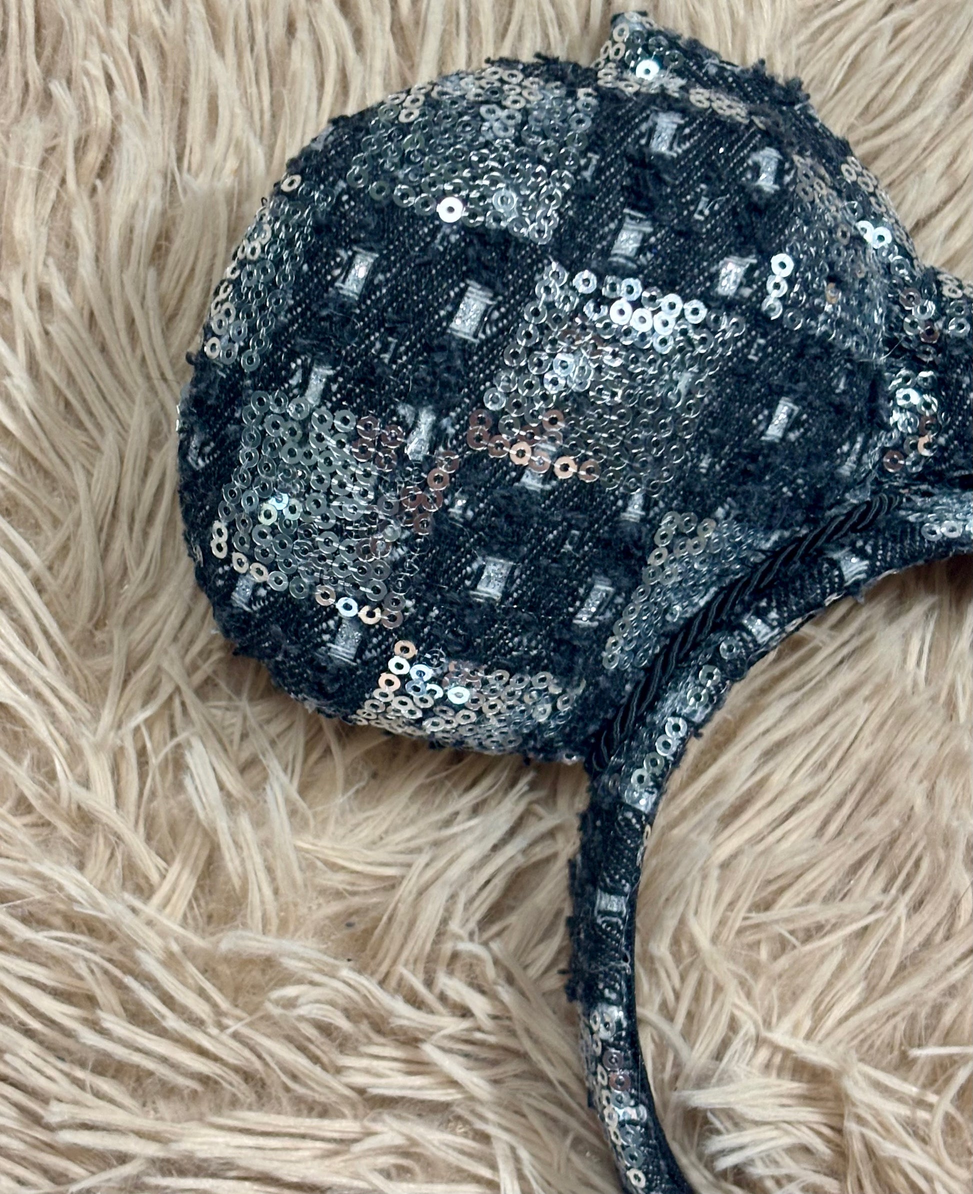 A black and silver checkered sequined headband with large bow ears.