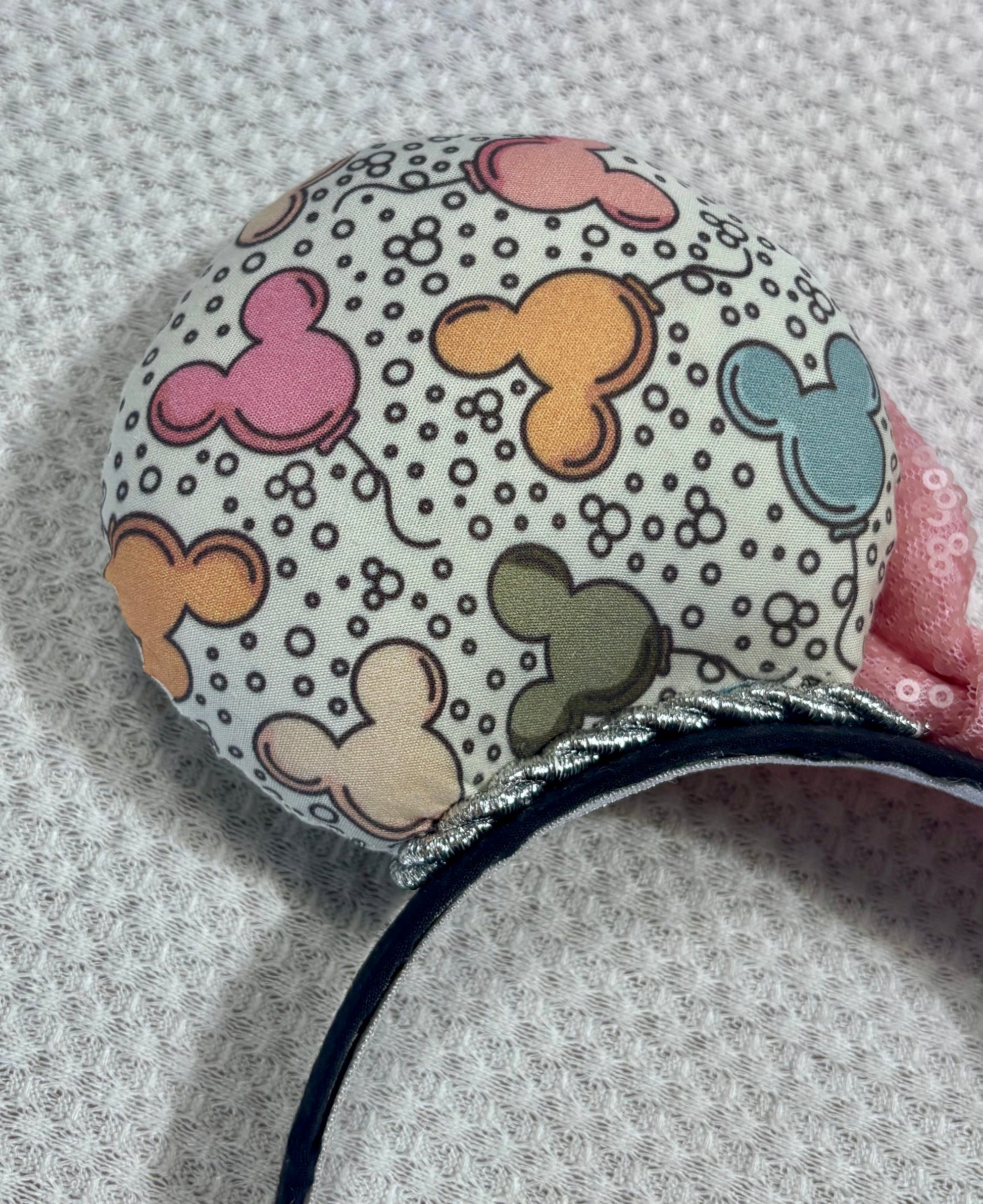 Close up of back left mouse ear. Handmade and ready to ship Mouse ears mouse balloons with a light pink sequin bow. Perfect for Main Street. Shown on a white background.