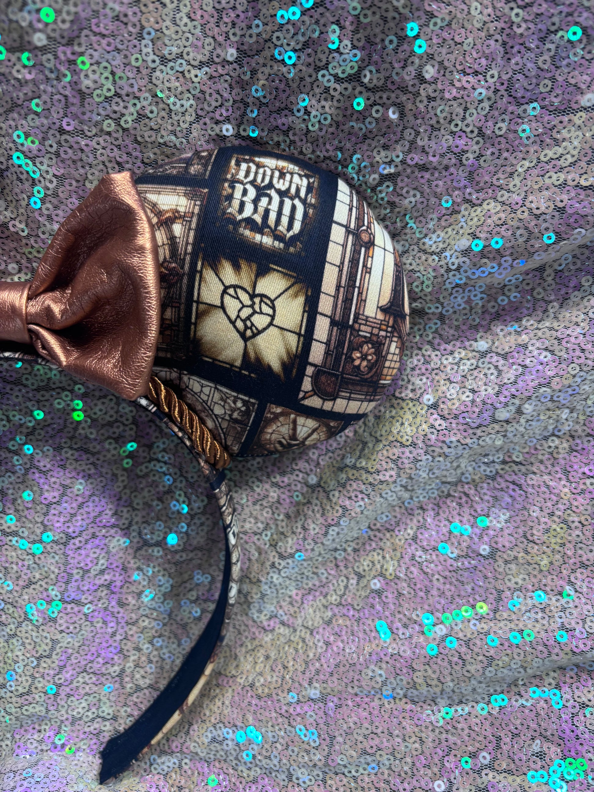 Mouse ears with a rose gold pleather bow and decorative elements on a textured purple background