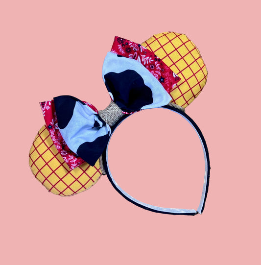 Handmade and ready to ship. Sheriff Woody Inspired mouse ears with the fabric on both the front and back that looks like his shirt. The fabric on the headband is black and is universal sized and fits most. The set has a bandana and cow print layered bow with brown trim along the inner ears to look like rope. Item is shown on a gold sequin background.