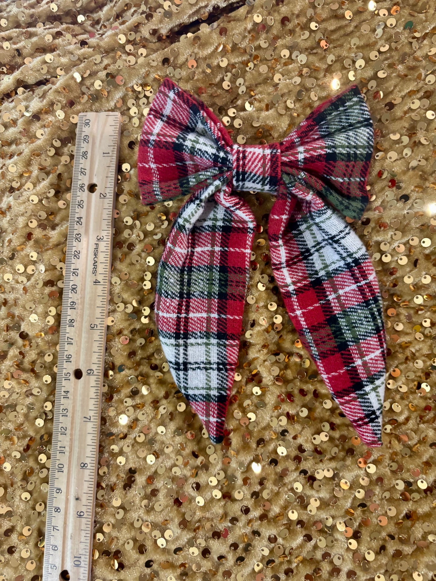 Plaid bow with a ruler for scale on a textured gold background