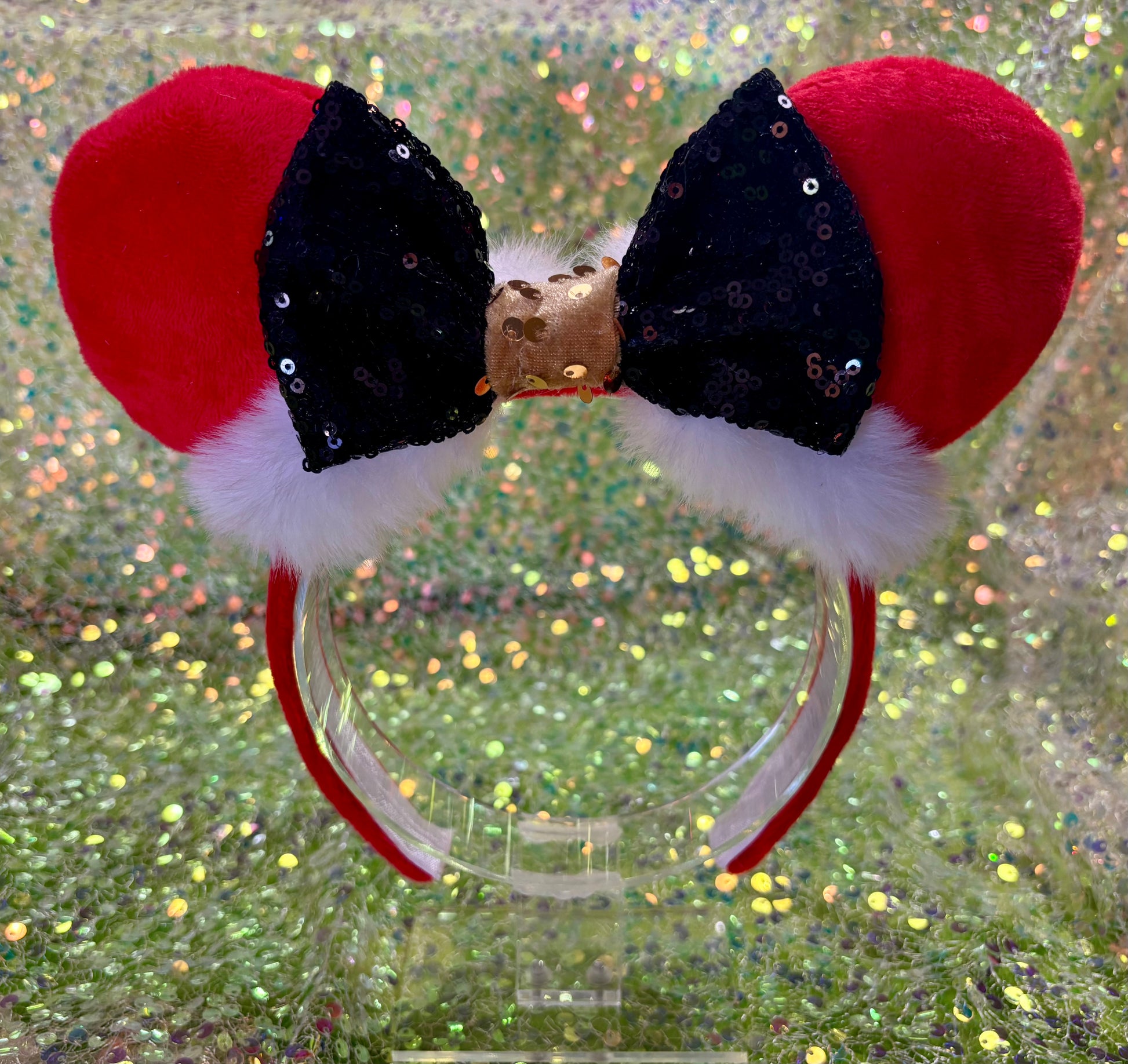 Red and black bow headband with fluffy white accents on a glittery background