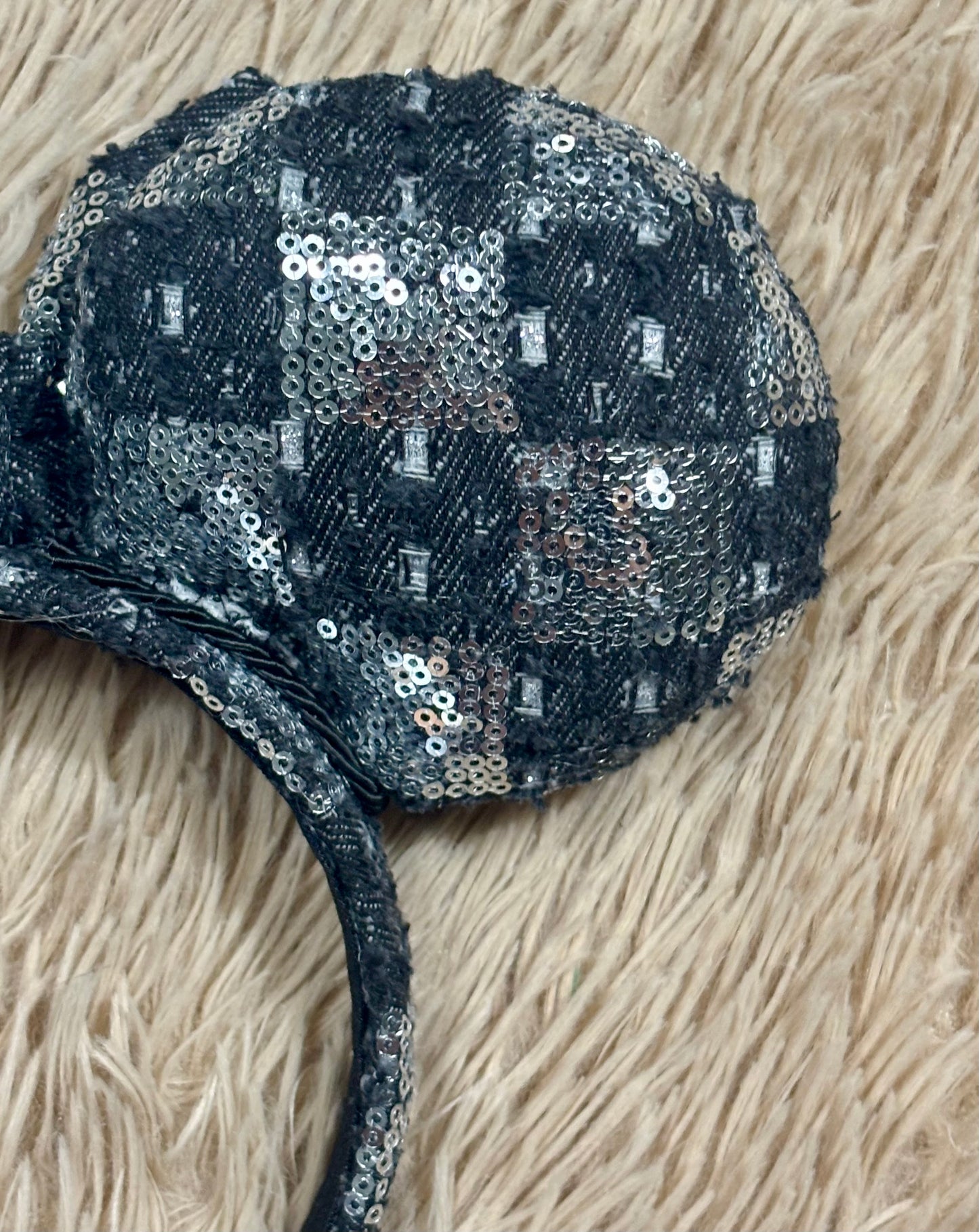 A black and silver checkered sequined headband with large bow ears.