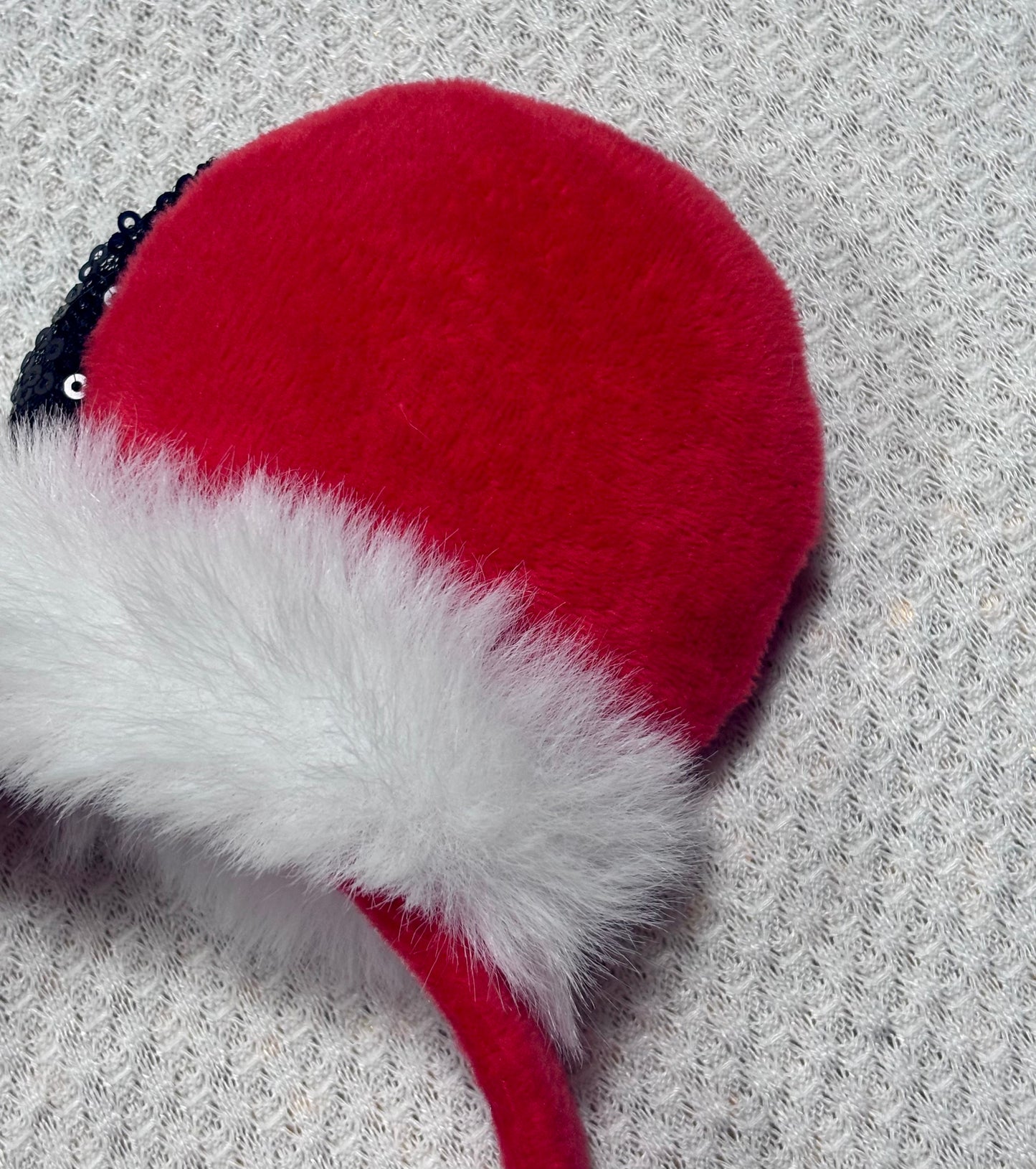 Minnie Mouse ears headband with red plush ears and black bow with gold middle and fluffy white trim on a white background