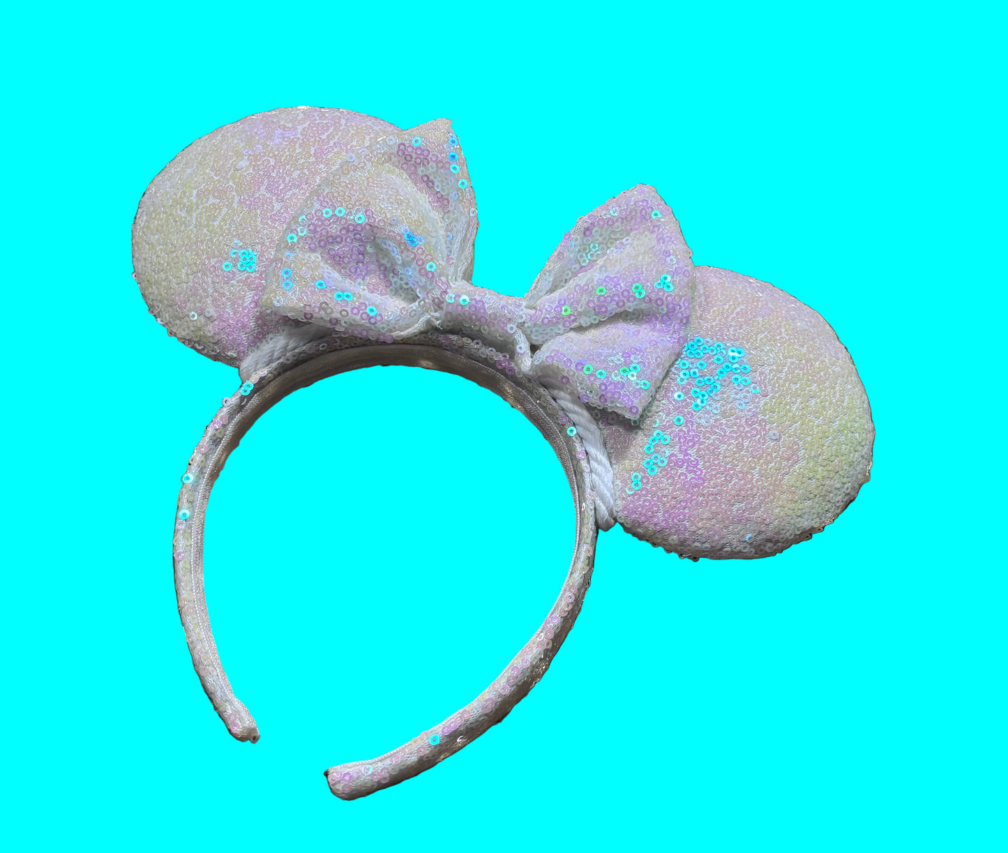 White Iridescent mouse ears with the fabric on both the front and back. The fabric is on the headband as well and is universal sized and fits most. The set has a matching iridescent bow sequin bow. 