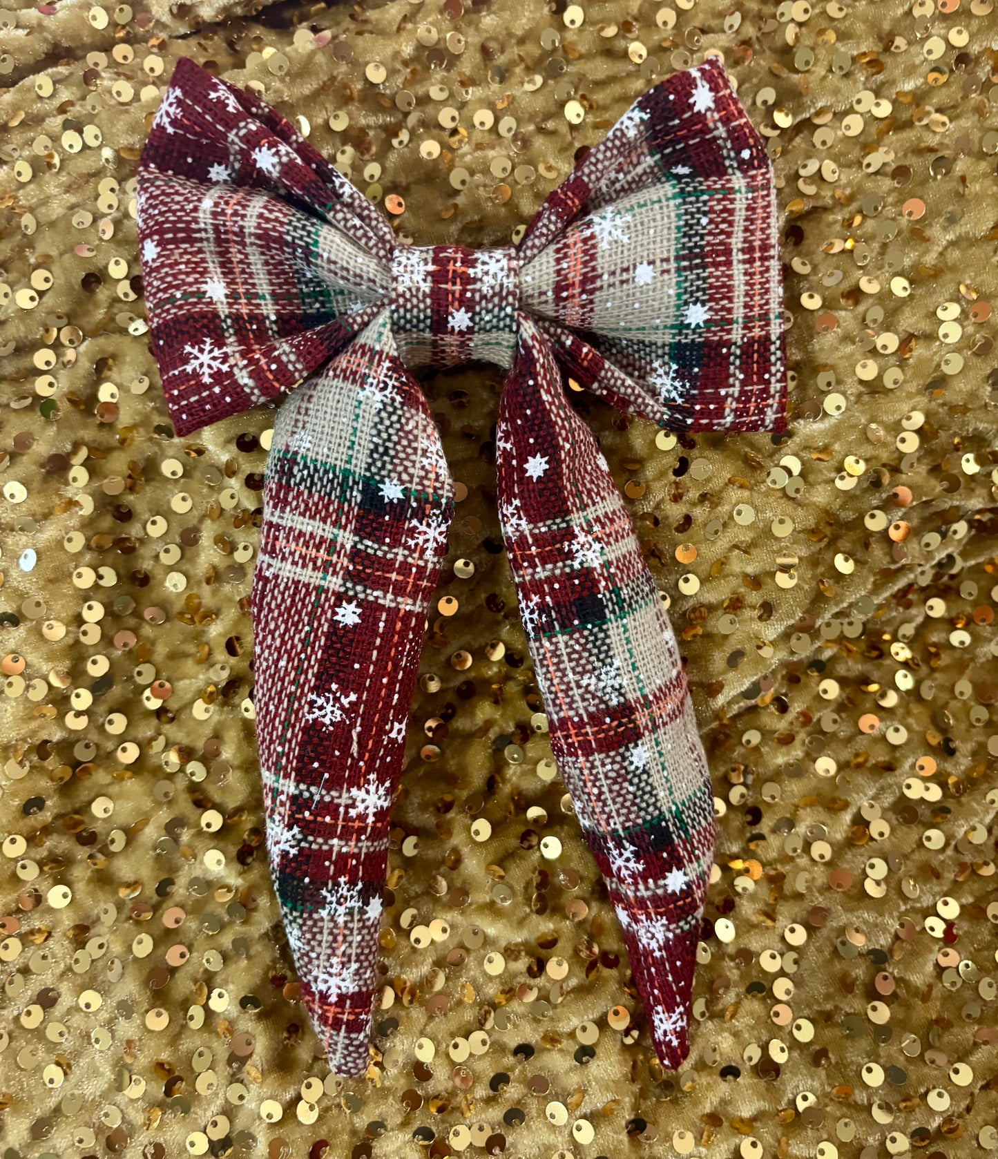 Plaid bow with snowflake details on a gold sequin background