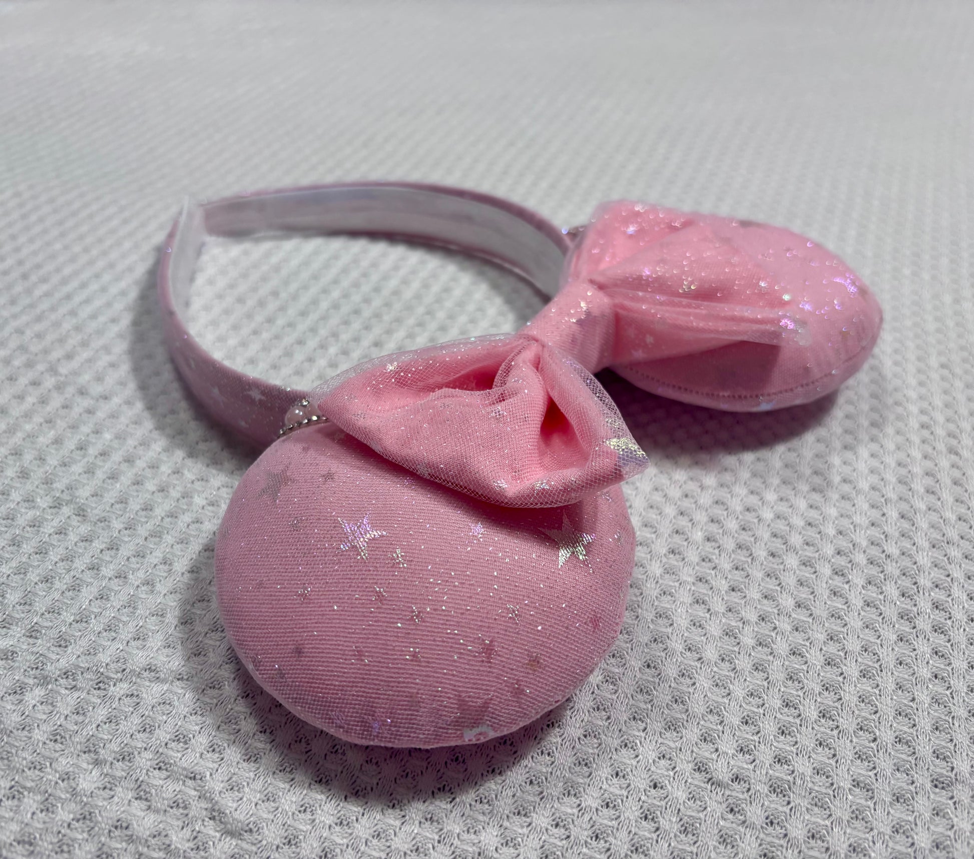 Handmade and ready to ship Pink Sparkling Iridescent fabric on pink to make mouse ears with the fabric on both the front and back along with the headband the is universal sized and fits most. The set has a matching bow, but you can request any sequin color in your order and I'll attach it. Item is shown on a white background.