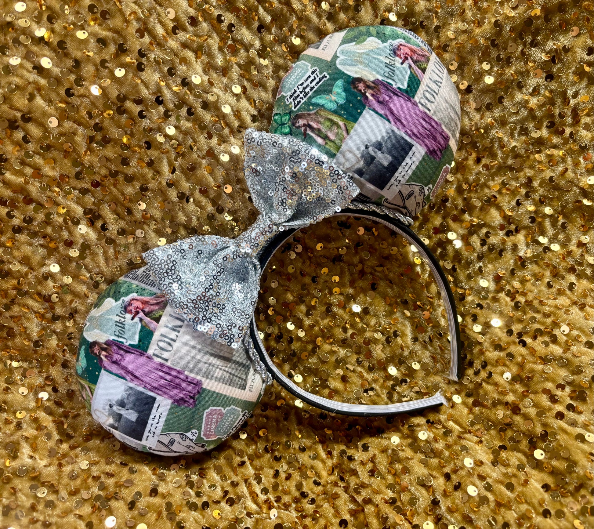 Decorative headband with newspaper folklore print and glittery bow on a gold sequin background