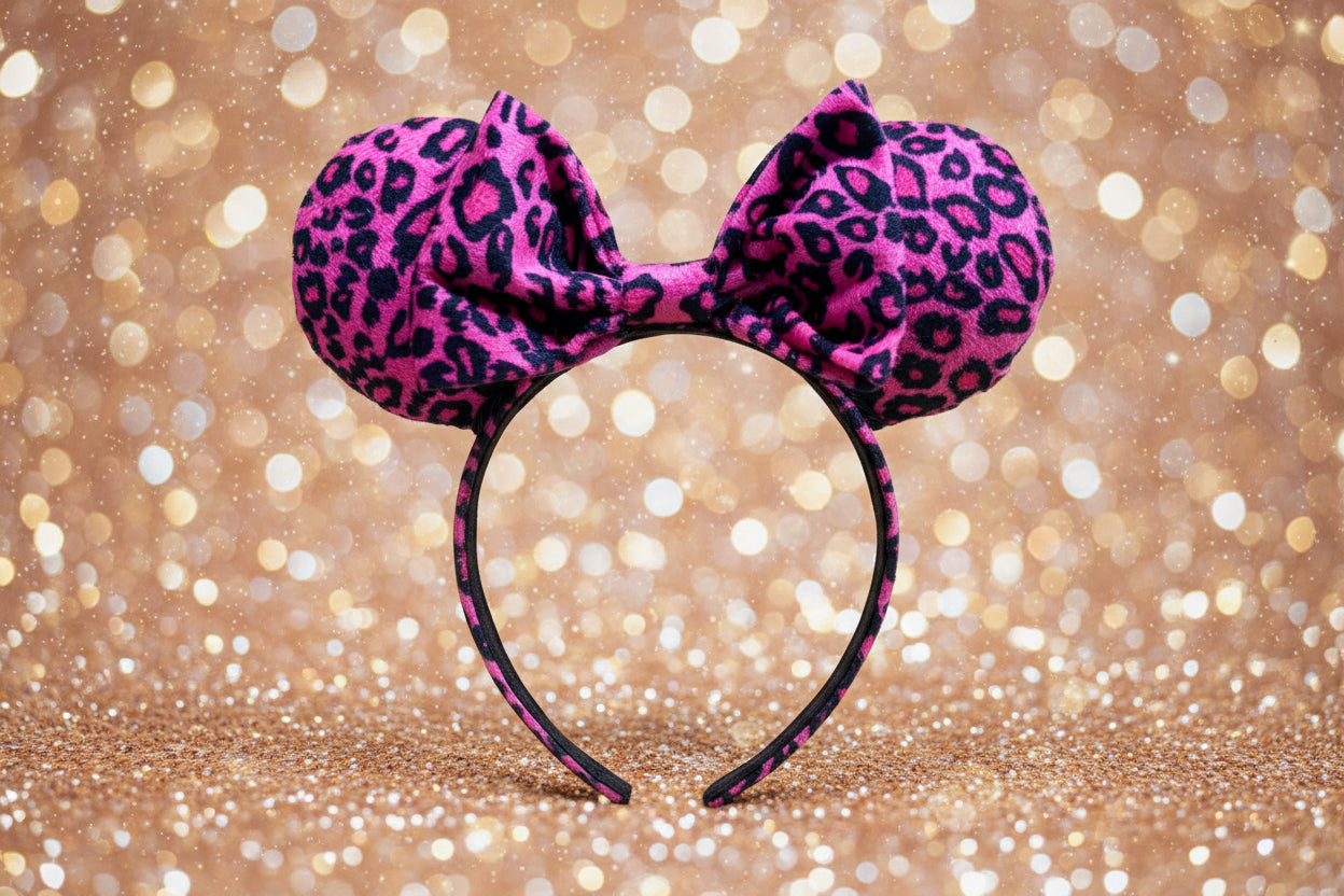 Pink leopard print mouse ears headband on a glittery gold background