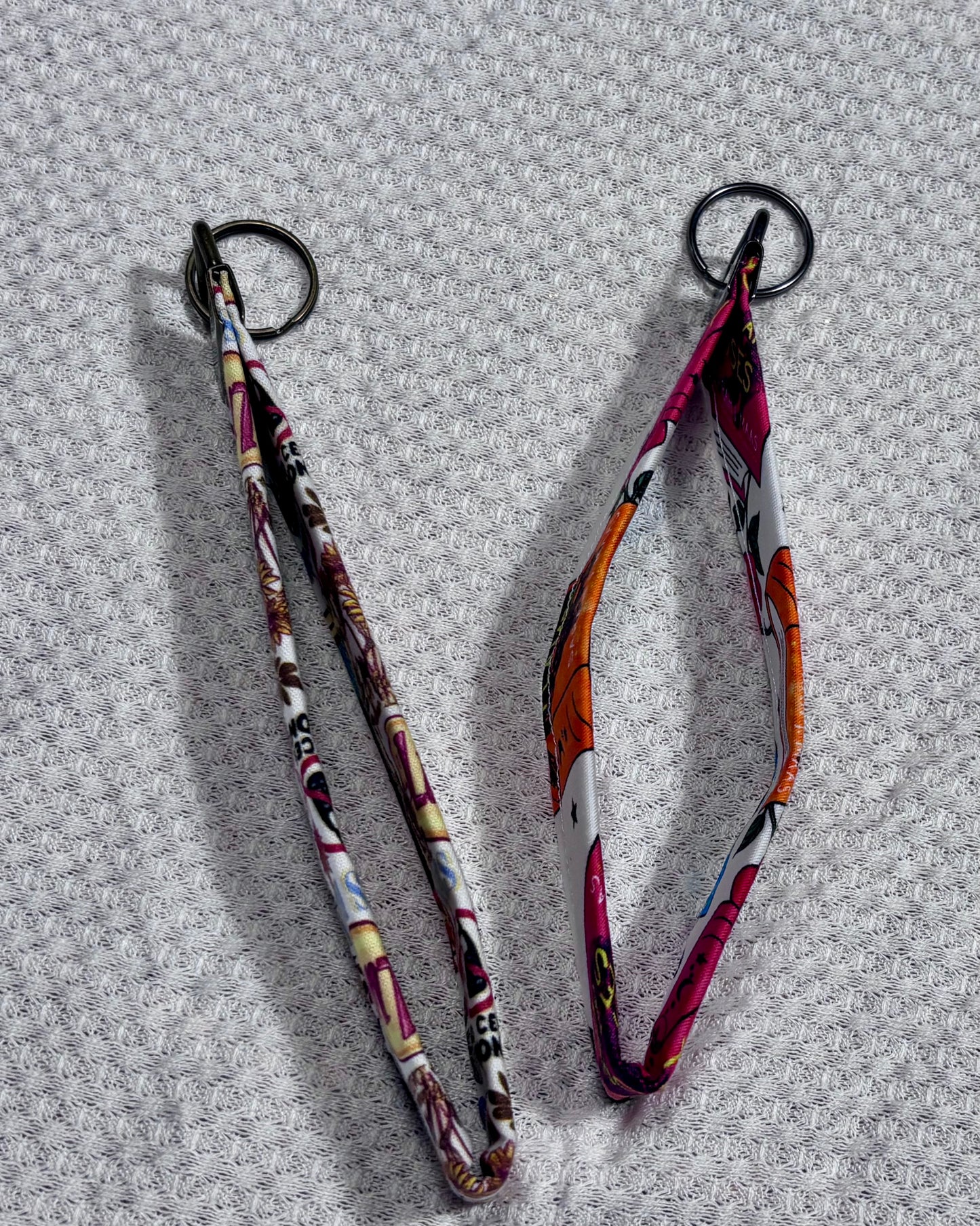 Two patterned lanyards on a textured gray background