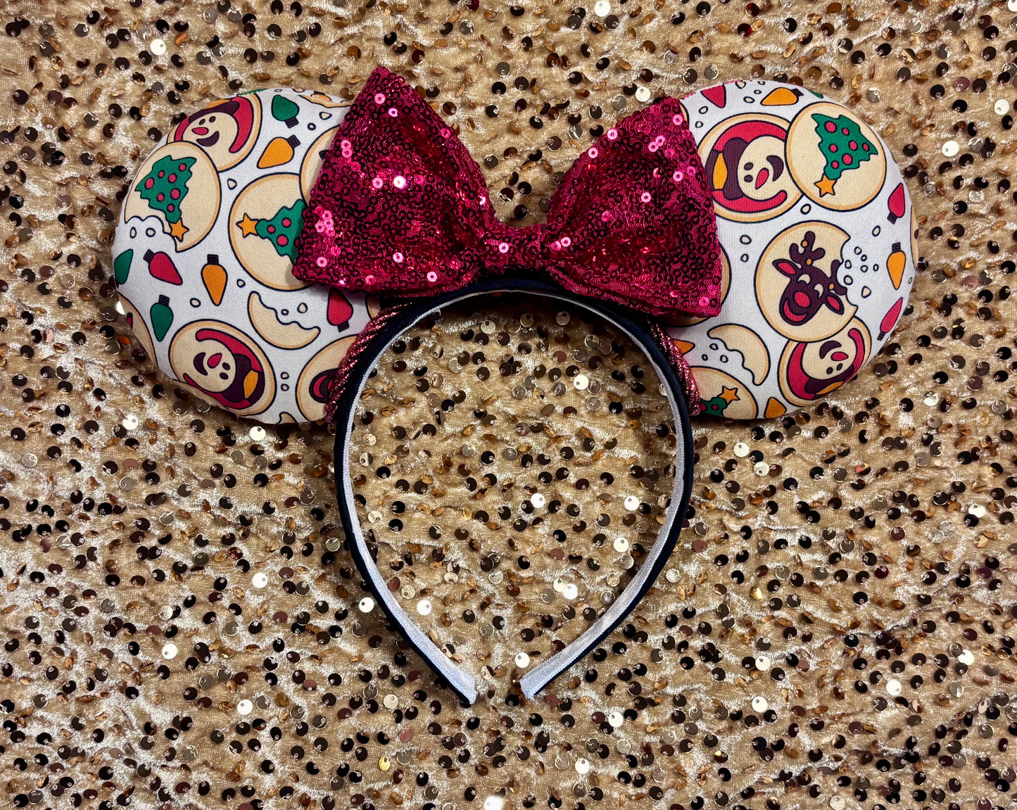 Christmas Sugar Cookie mouse ears with the fabric on both the front and back. The headband is black universal sized and fits most. The set has a red sequin bow. Item is shown on a gold sequin background