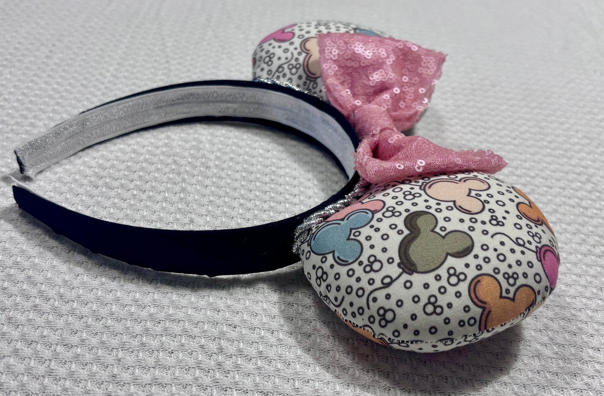 Side view of Handmade and ready to ship Mouse ears mouse balloons with a light pink sequin bow. Perfect for Main Street. Shown on a gold white background.