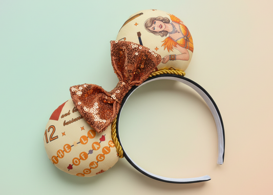 Showgirl fabric in orange mouse ears on a black headband with orange twisted trim and orange sequin bow. Shown on a gradient background