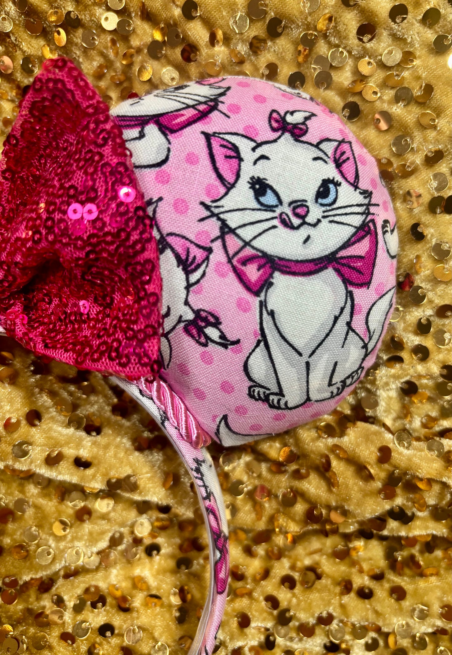 Close up of the other front side of ear. Handmade and ready to ship Marie Inspired Mouse ears with images of her on the front and back of mouse ears shown with a Hot Pink sequin bow option. The headband has a matching Marie poly cotton fabric and is a universal sized headband. 