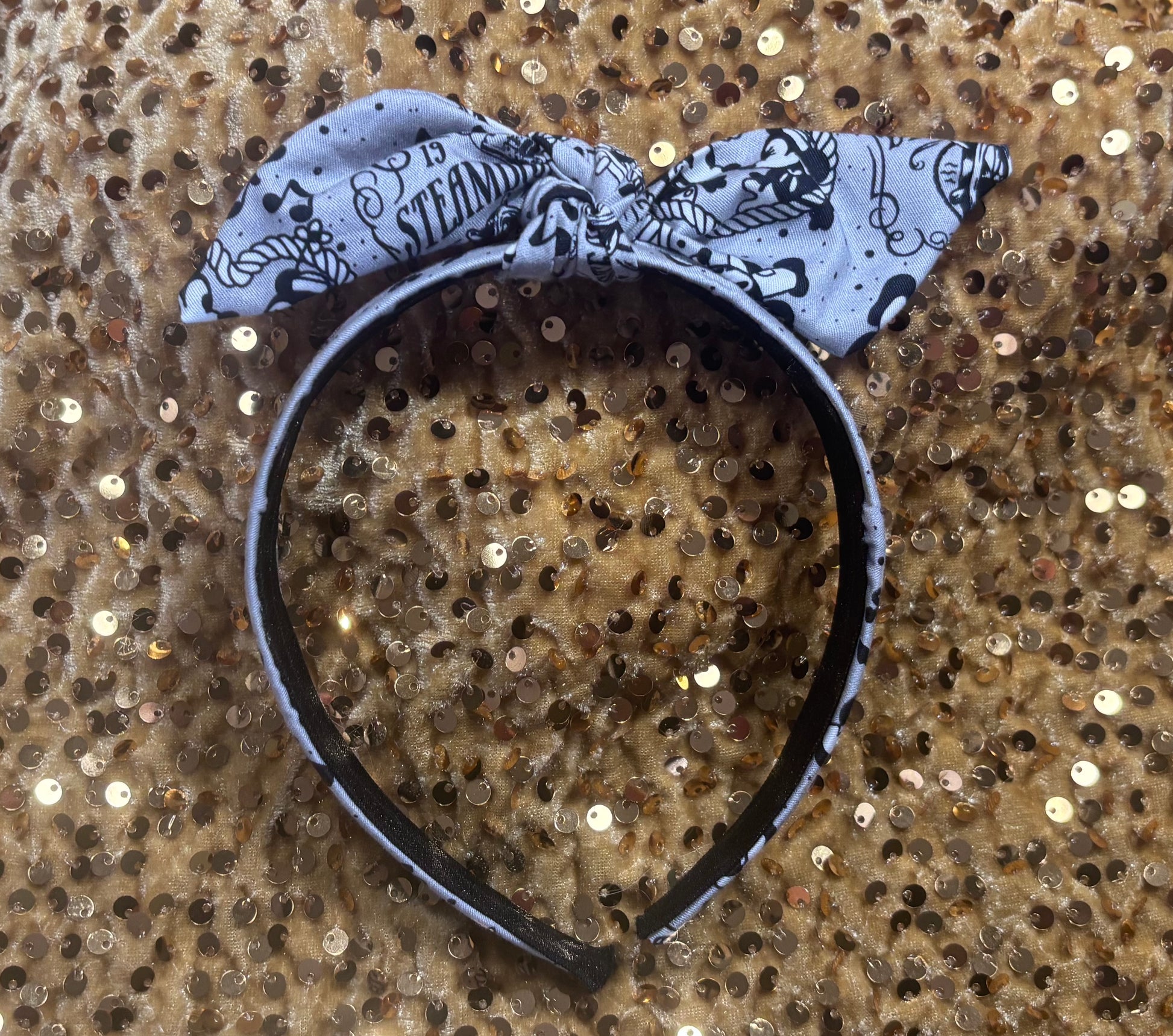 Twisted Bow Headband with a Steamboat theme on a glittery gold background