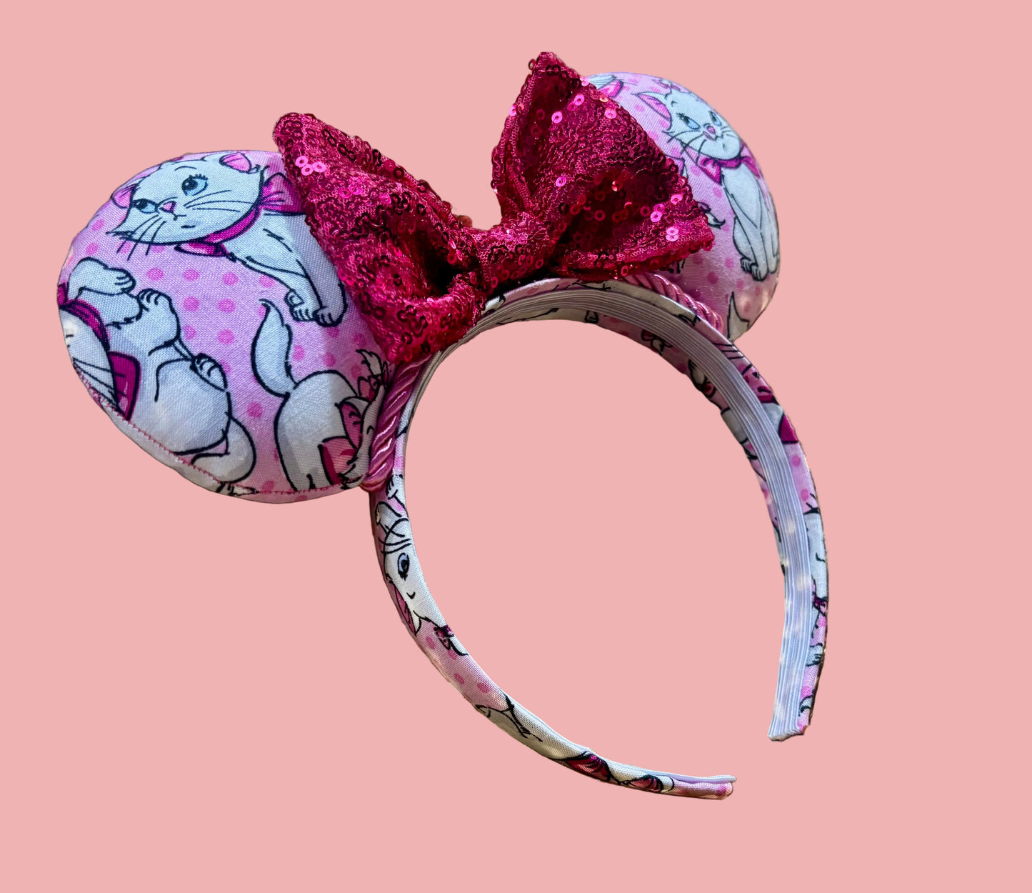Handmade and ready to ship Marie Inspired Mouse ears with images of her on the front and back of mouse ears shown with a Hot Pink sequin bow option. The headband has a matching Marie poly cotton fabric and is a universal sized headband. 