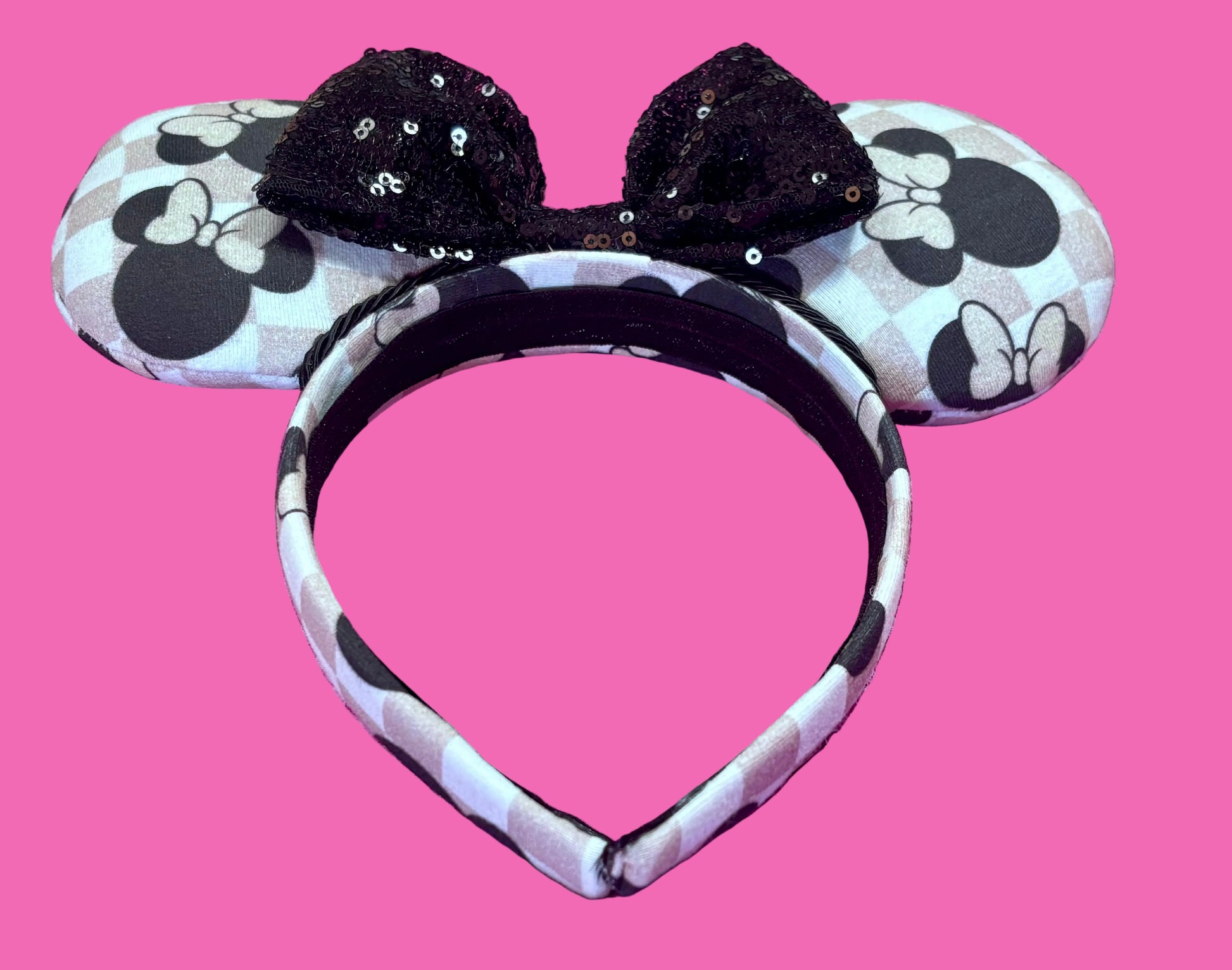 Mouse ears headband with black bow on a pink background.