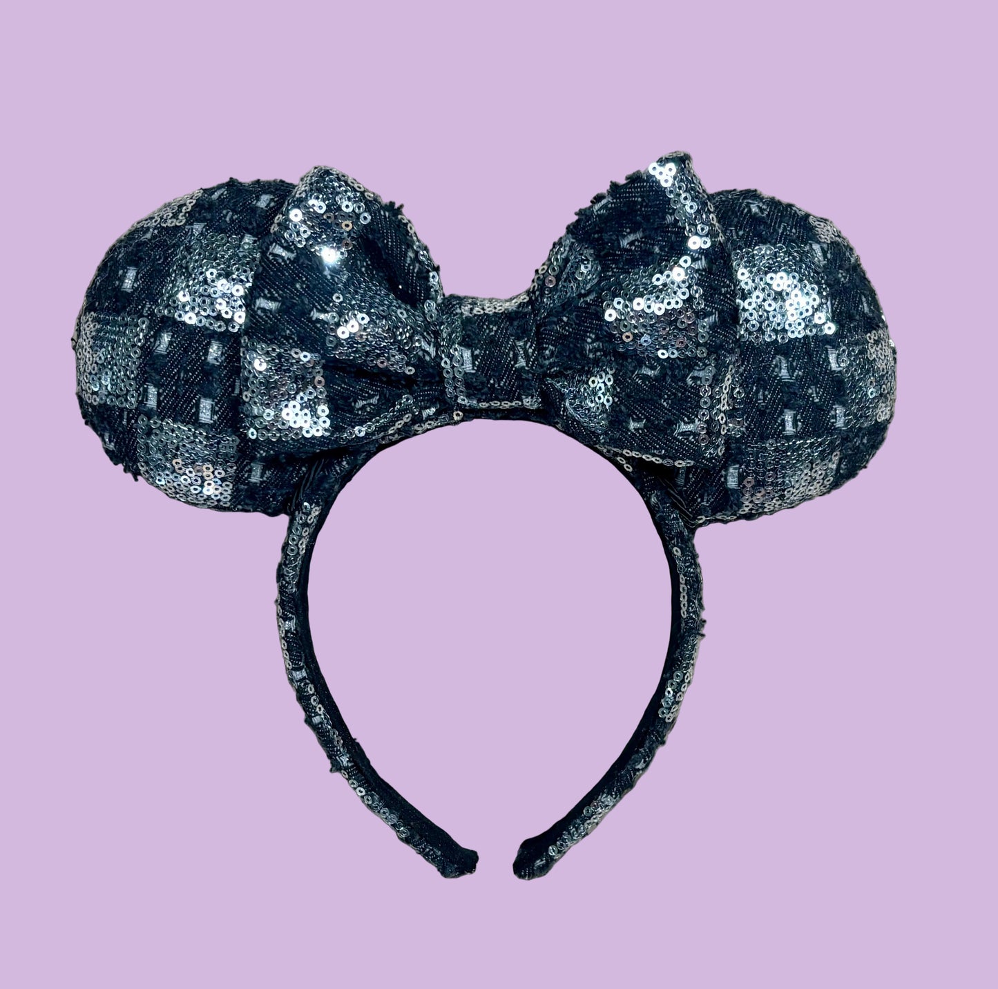 A black and silver checkered sequined headband with large bow ears.