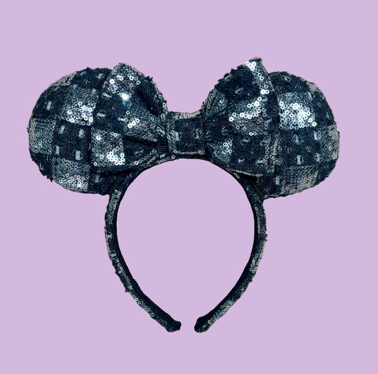 A black and silver checkered sequined headband with large bow ears.