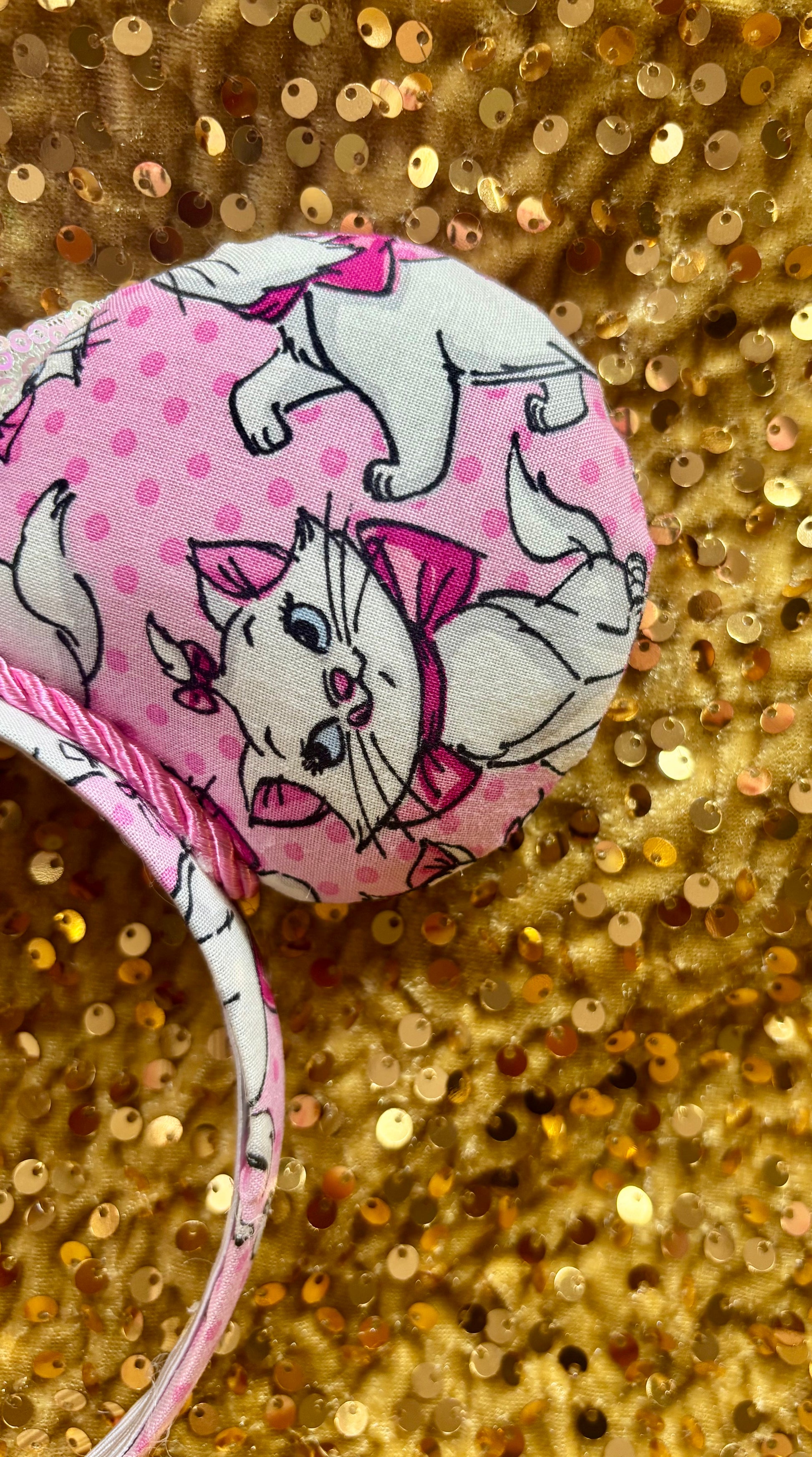 Pink mouse ear headband with white bow shown on a gold glitter background