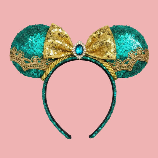 Handmade, and ready to ship. Jasmine inspired Mouse ear headband with teal sequin fabric on the front and back of ears with a gold sequin bow with a teal embellishment in the middle of bow. gold along the ears and the trim as well. Mouse ears are on a Universal sized headband that also has teal on it. 
