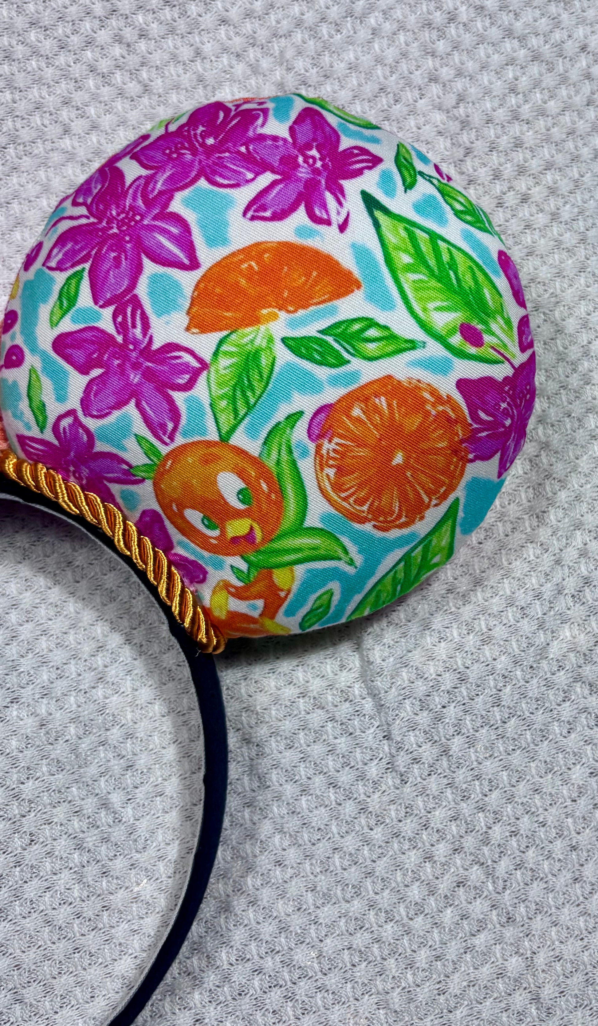 Colorful floral and fruit patterned headband on a textured gray background