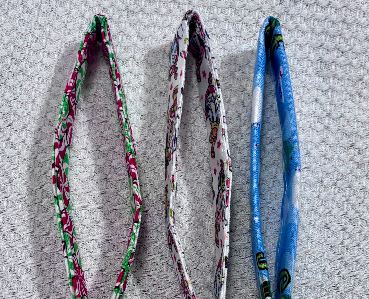 Three colorful fabric straps that make the keychain wristlet on a textured gray surface