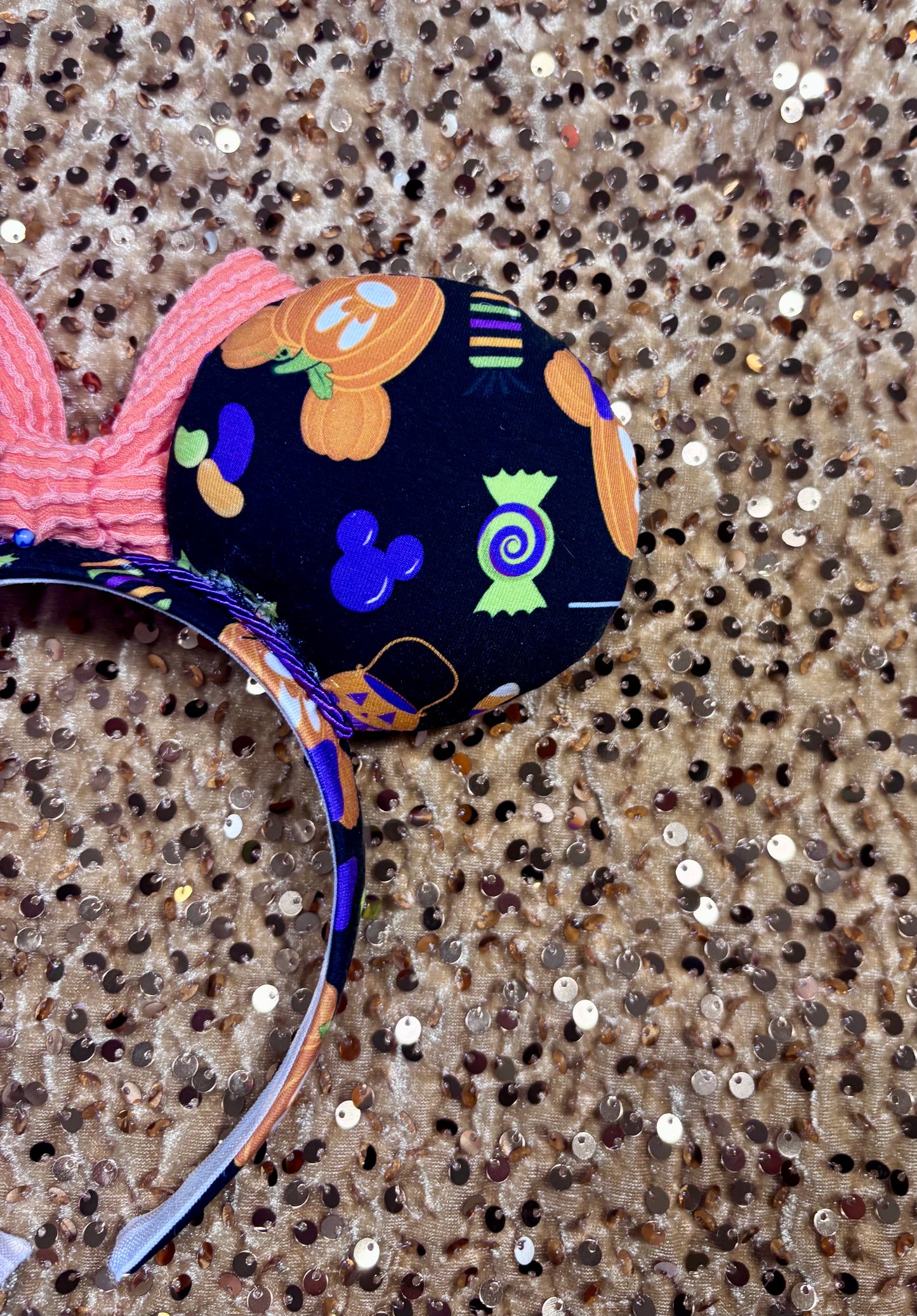 Mouse ear headband with colorful design on a glittery surface. Shown from a back right mouse ear view. 