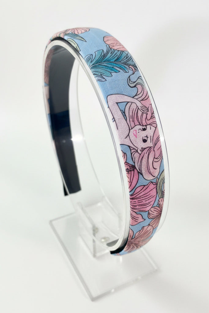 Decorative headband with floral and mermaid design on a white background.