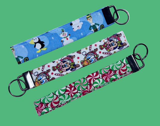 Three colorful keychains with different Christmas theme designs: Elf, Christmas Pals and Peppermint print on the keychains. Handmade and ready to ship.