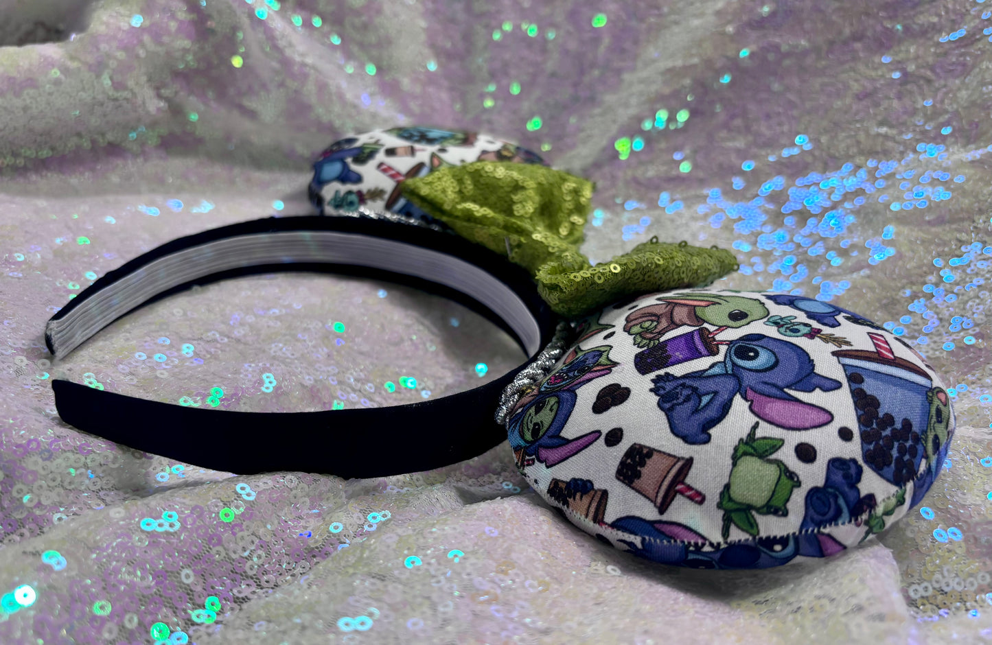 Handmade and ready to ship. Stitch and Baby Yoda are drinking coffee on the front and back with a lime green sequin bow. Shown on a white background.