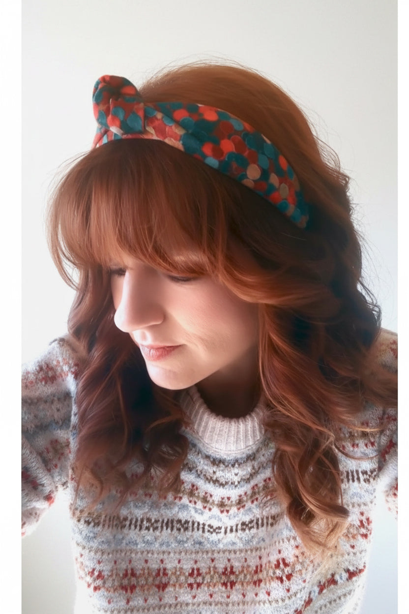 Model Tam wearing the Christmas Colors patterned headband and a sweater with a white background.