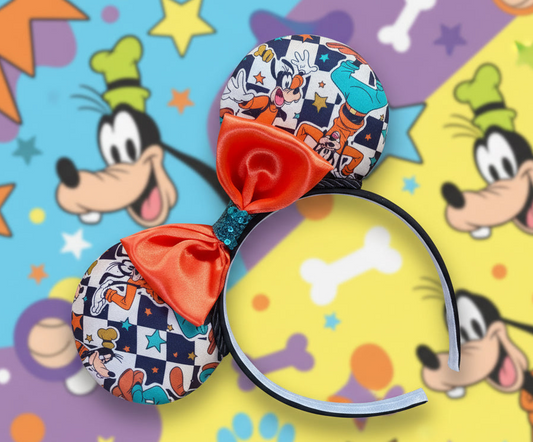 Colorful mouse ears with Goofy cartoon character with checkered print on it and an orange satin bow with turquoise middle. design is shown on a multicolored background