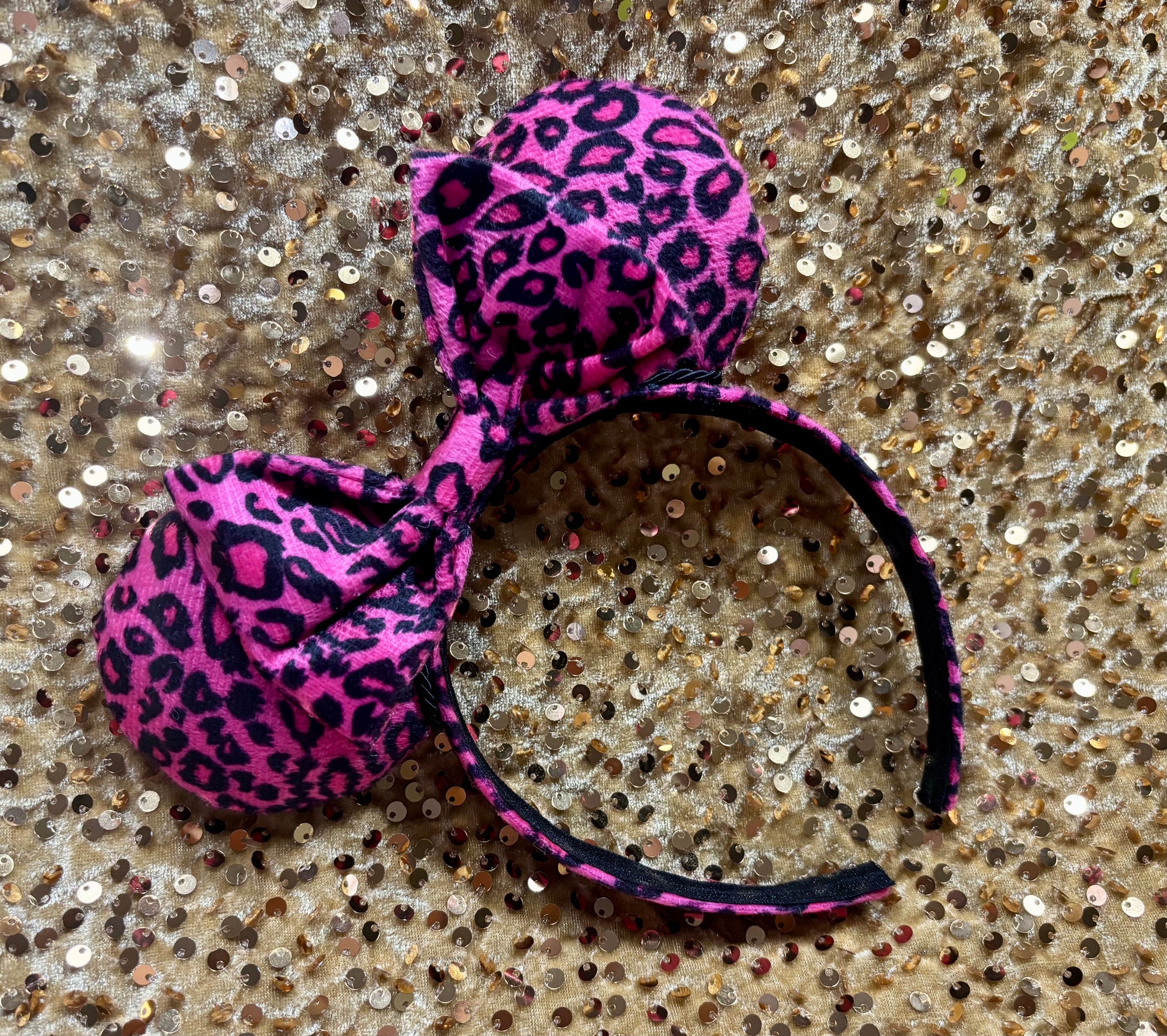 Pink leopard print headband on a glittery surface