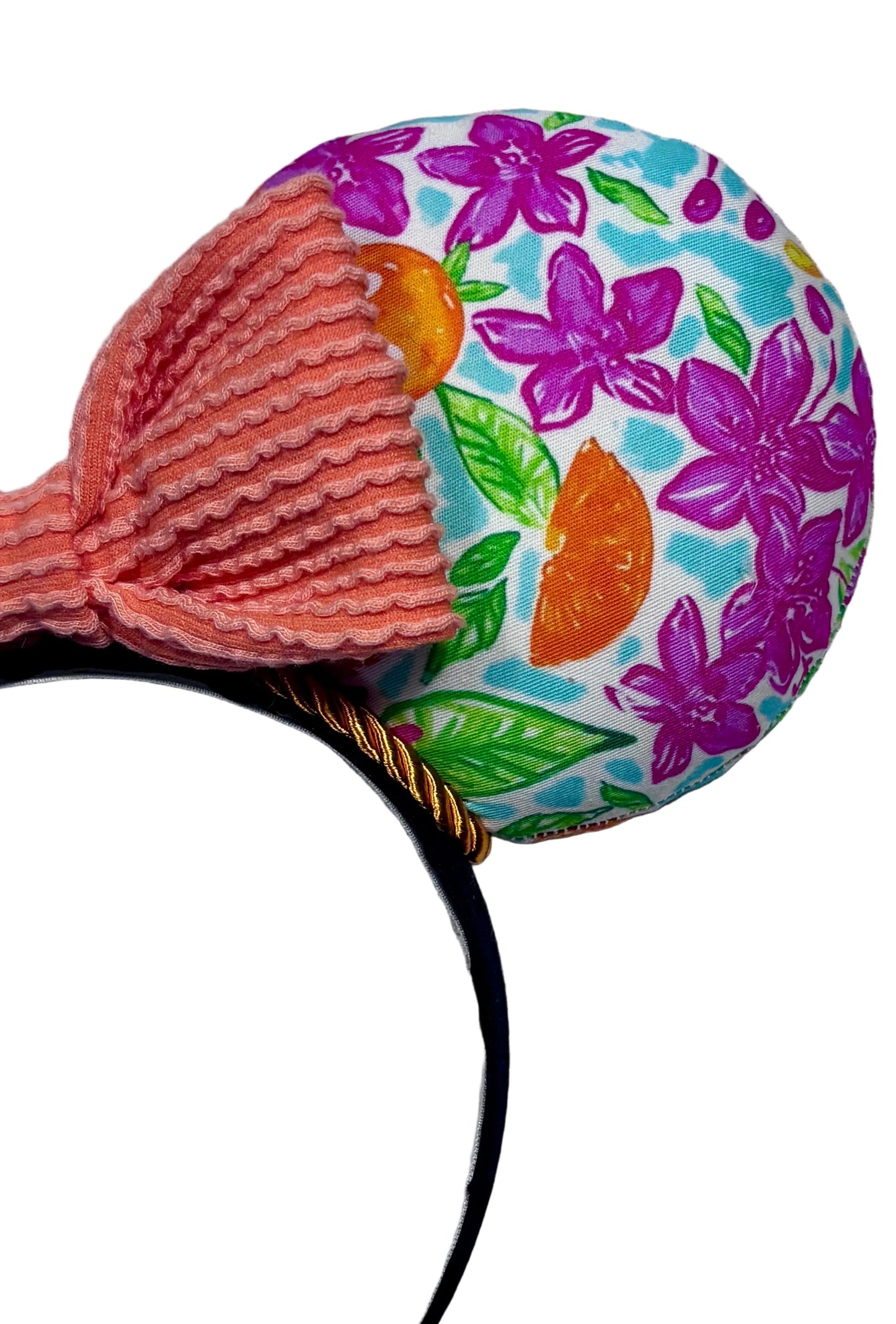 Colorful floral-patterned Orange Bird mouse ears with an orange waffle print bow on a white surface