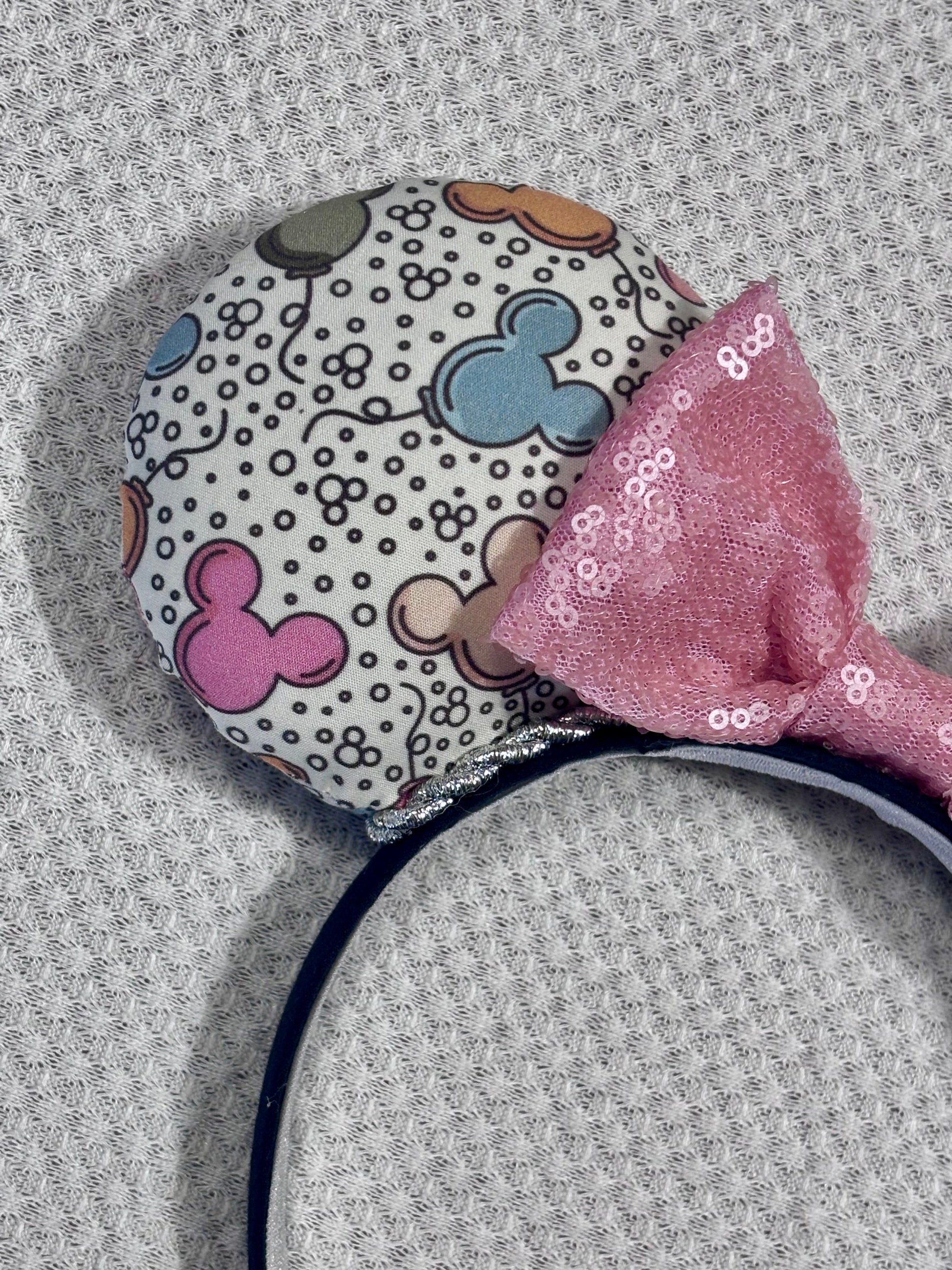 Close up of front of mouse ear and detail of mouse balloon fabric along with the silver trim and pink sequin bow.