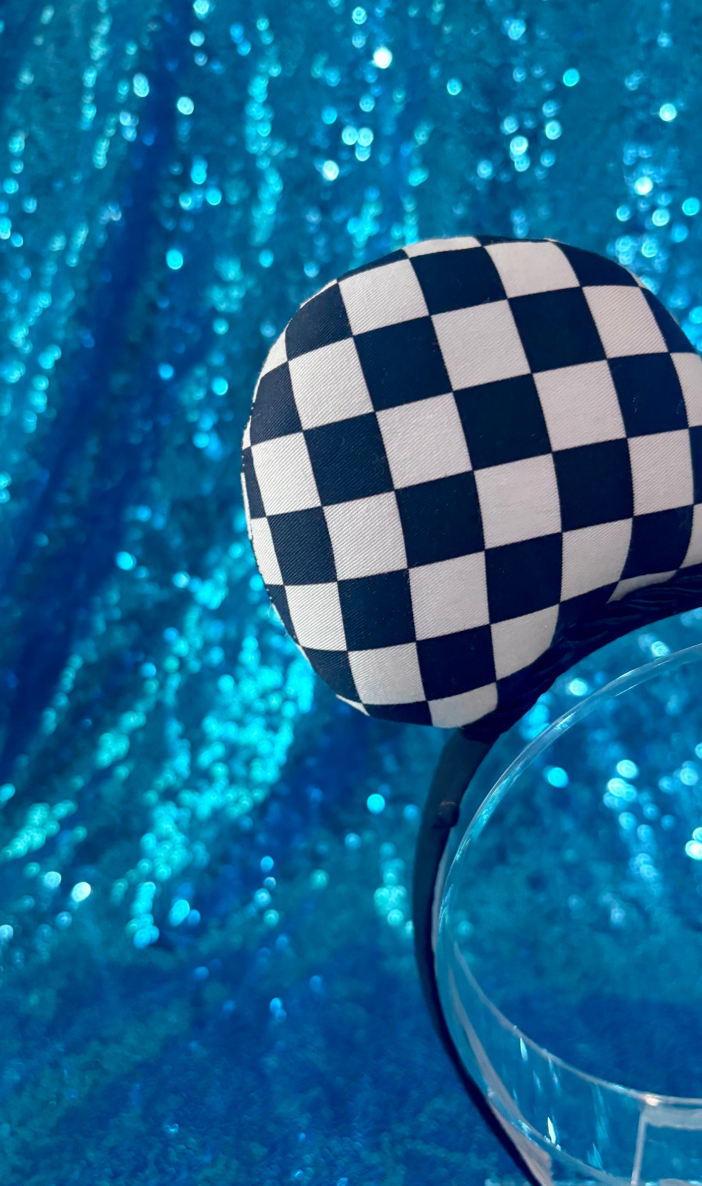 Checkered handmade mouse ears on a black universal headband, shown on a blue background.