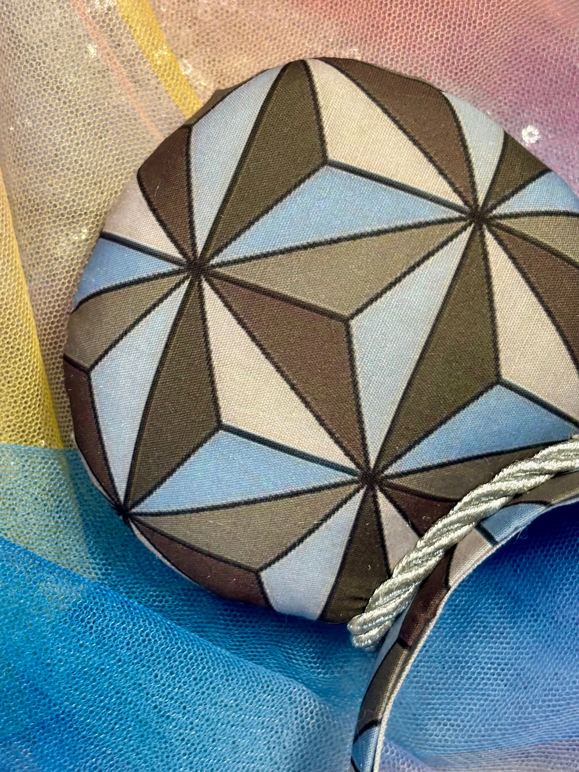 Mouse ear headband with a geometric design inspired by Spaceship Earth ride and a white iridescent bow on a colorful background