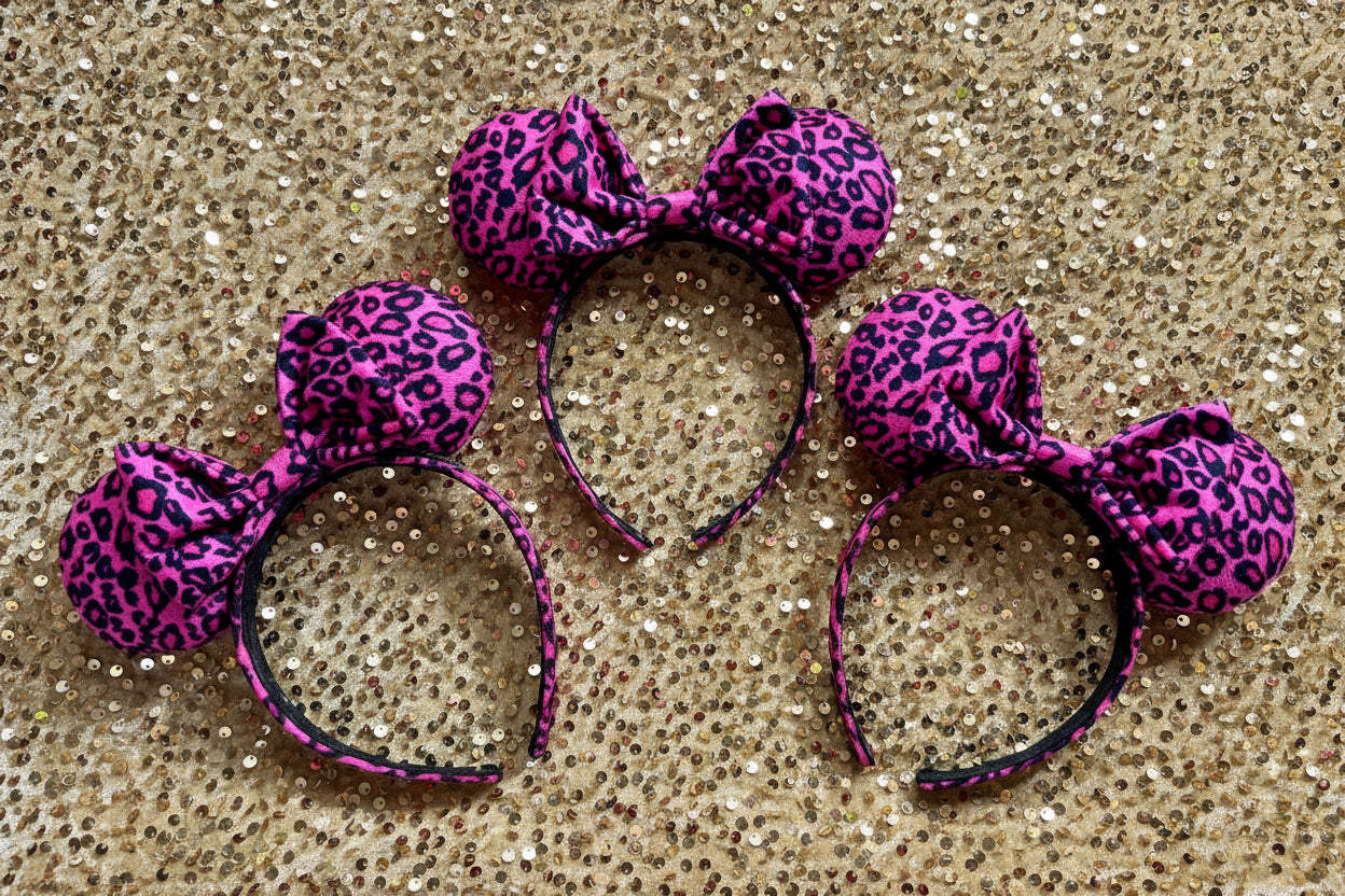 Pink leopard print mouse ears on a glittery gold background