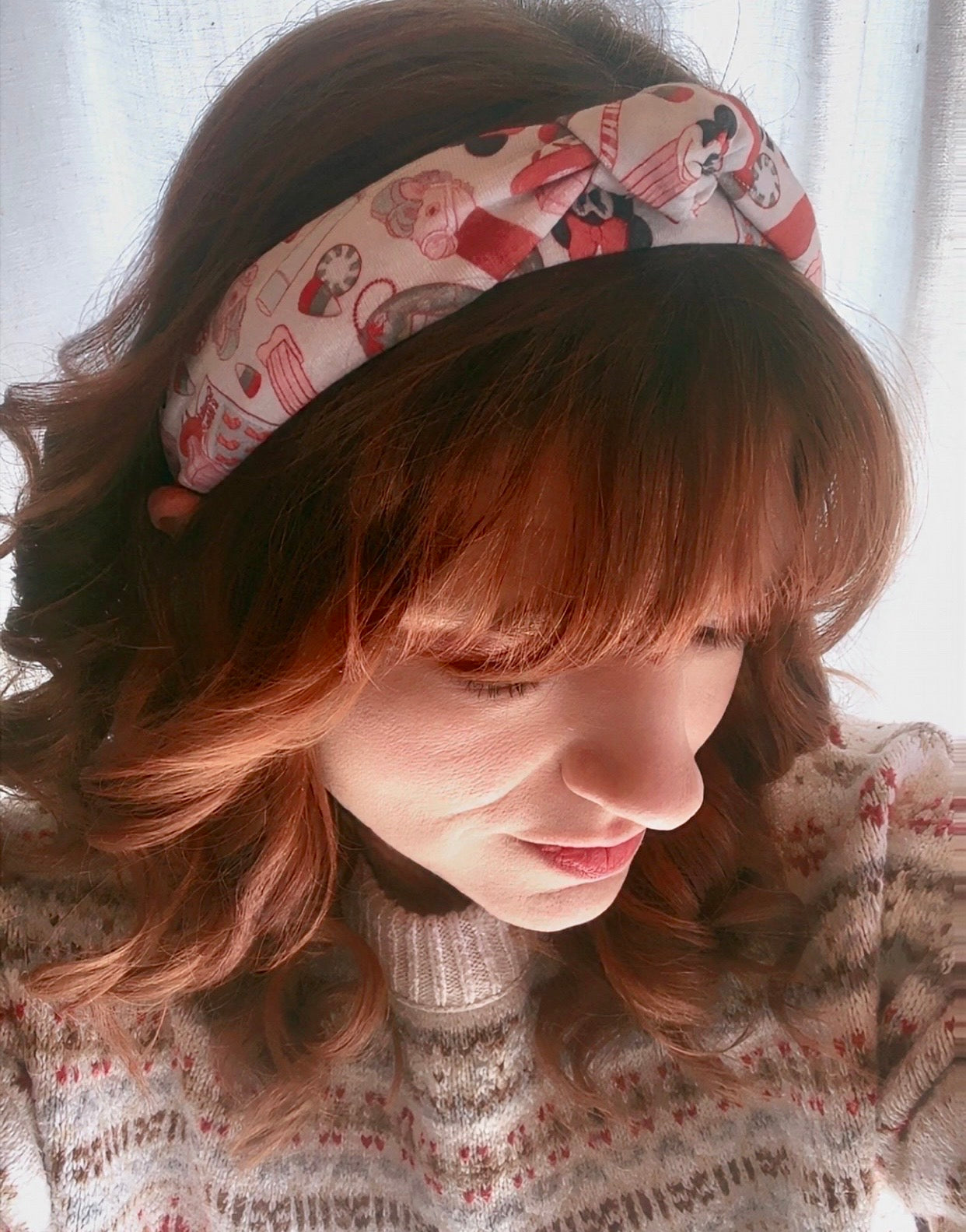Model Tam wearing a patterned Stocking Stuffers headband with a soft focus background.