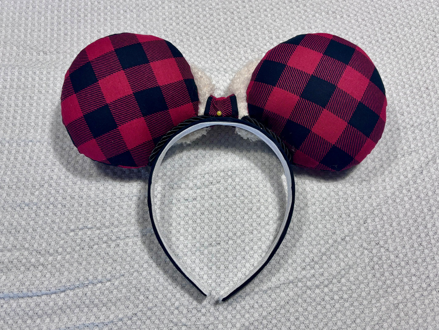 Handmade and ready to ship. Back side of Buffalo Plaid mouse ears on both the front and back. On a black headband that is universal sized. The set has an off-white soft bow with buffalo plaid middle. Item is shown on a white background.