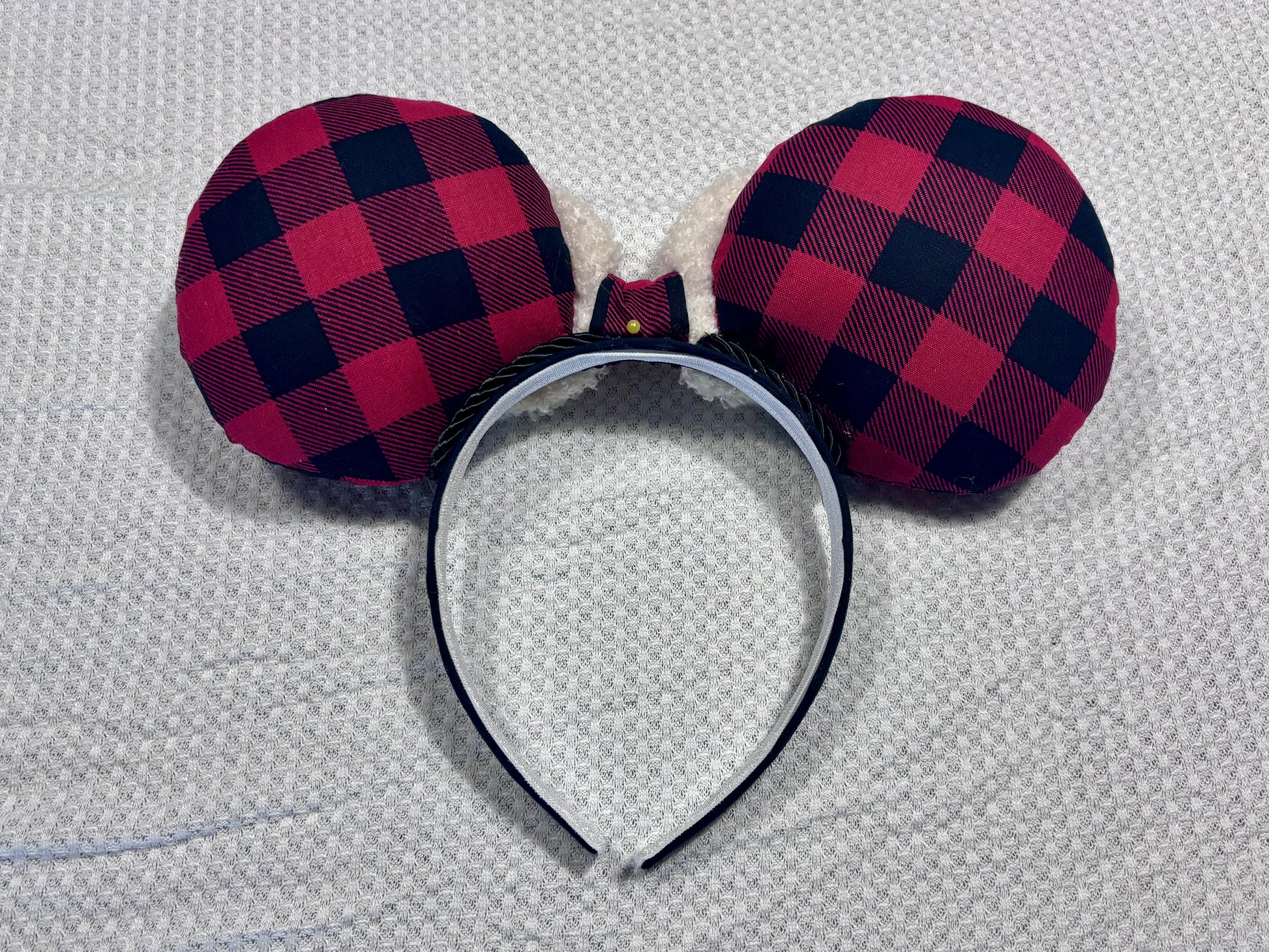 Handmade and ready to ship. Back side of Buffalo Plaid mouse ears on both the front and back. On a black headband that is universal sized. The set has an off-white soft bow with buffalo plaid middle. Item is shown on a white background.